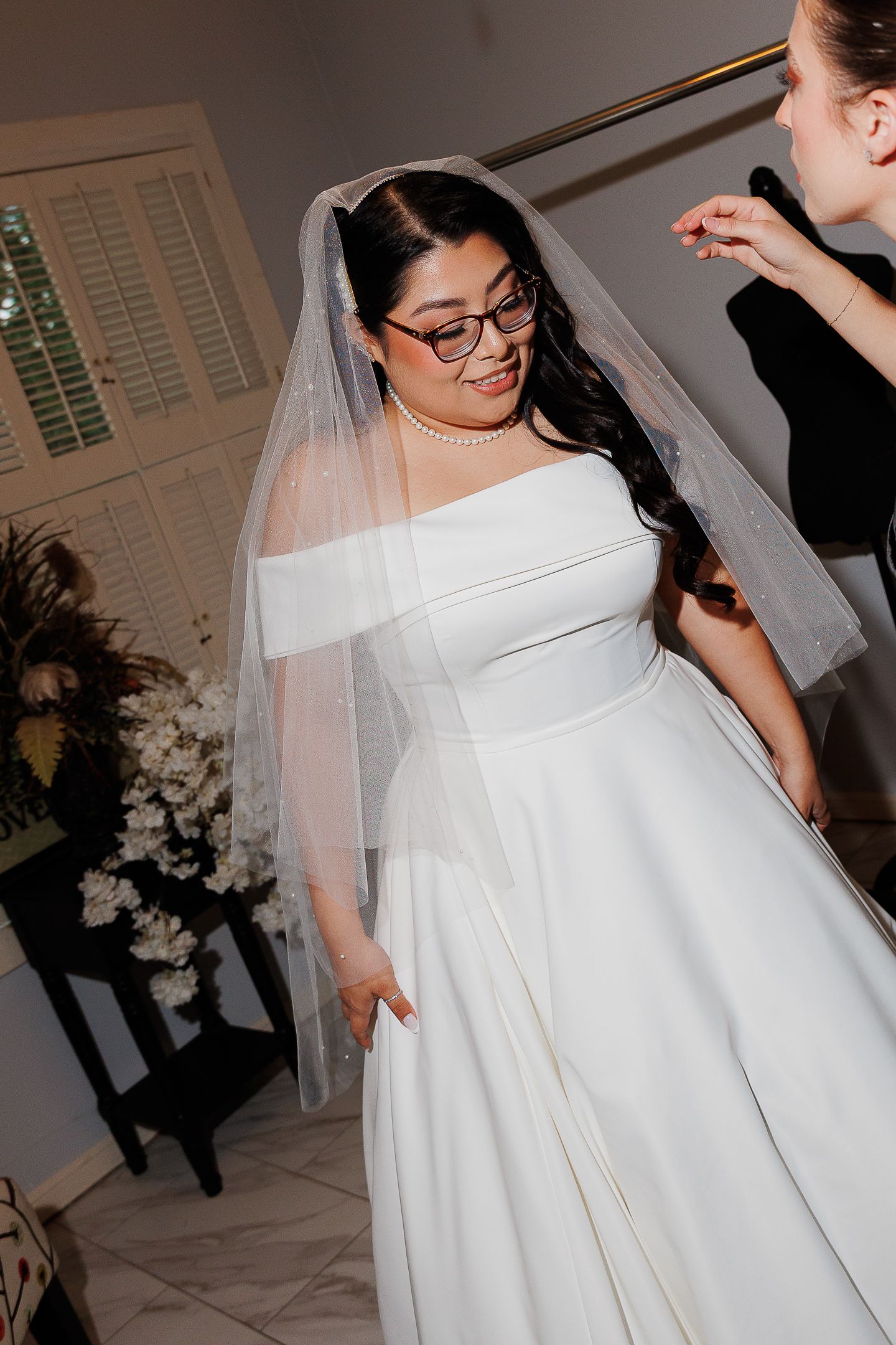 A bride in a classic white wedding dress and veil dances joyfully at her wedding reception.