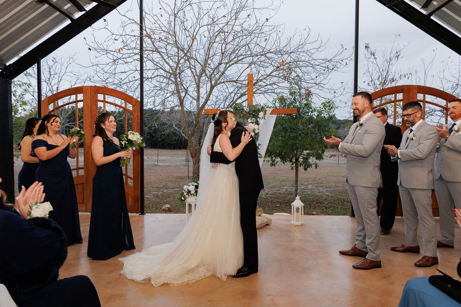 Wedding party dances together in an elegant outdoor pavilion during a reception celebration.