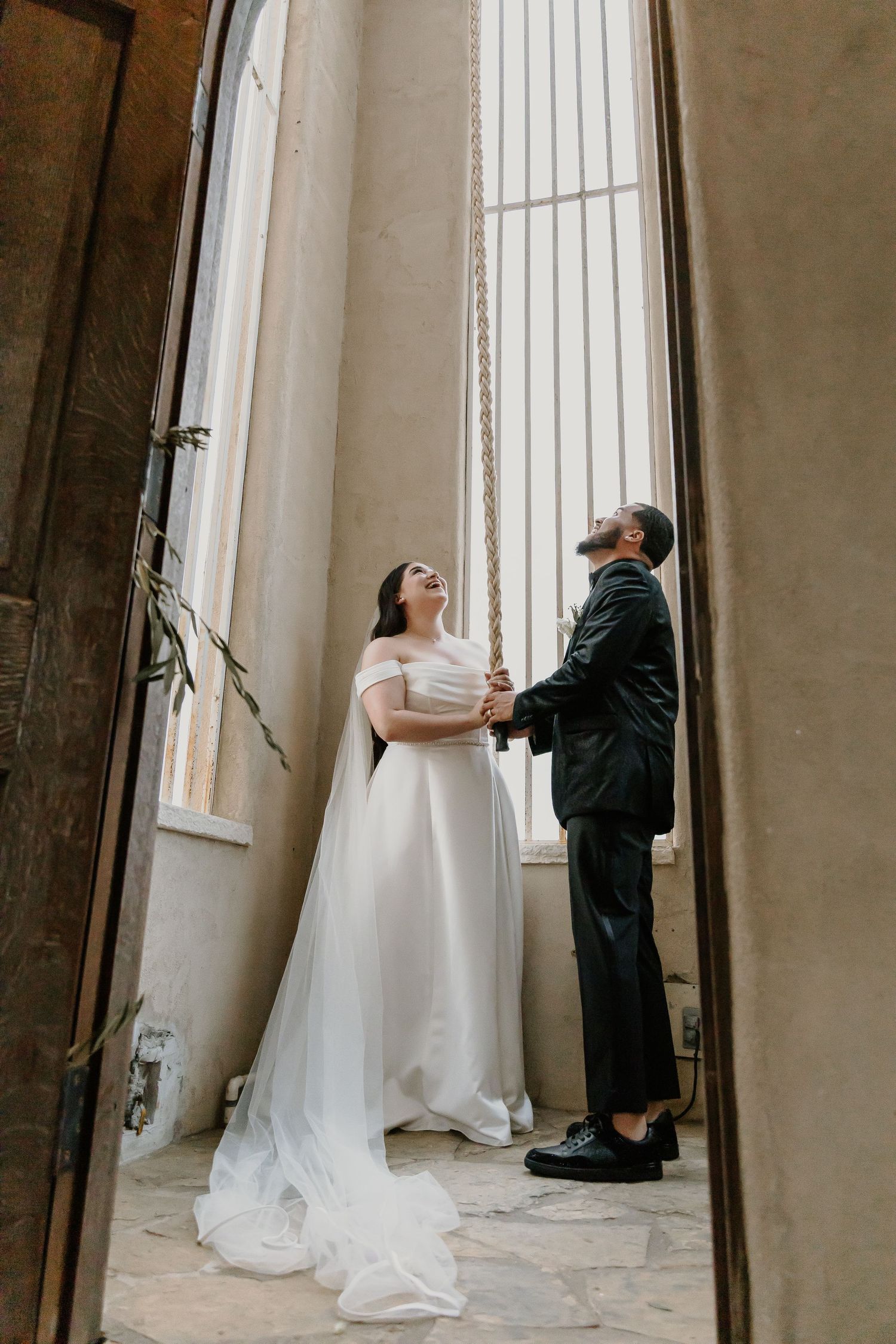 Wedding couple standing in dramatic architectural doorway looking upward.