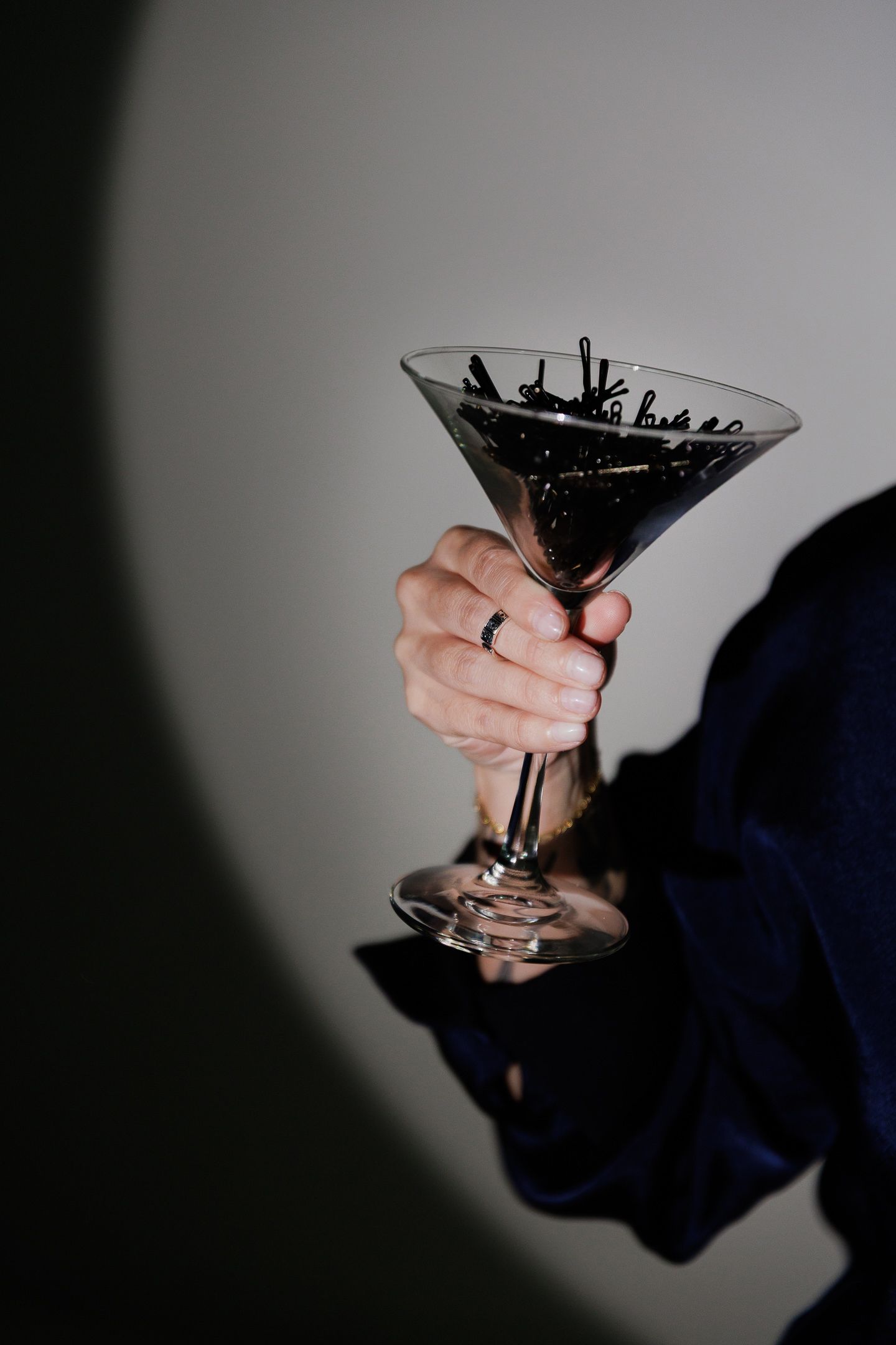 A sequence of black and white photographs showing a martini glass being held at different angles against a shadowy background.