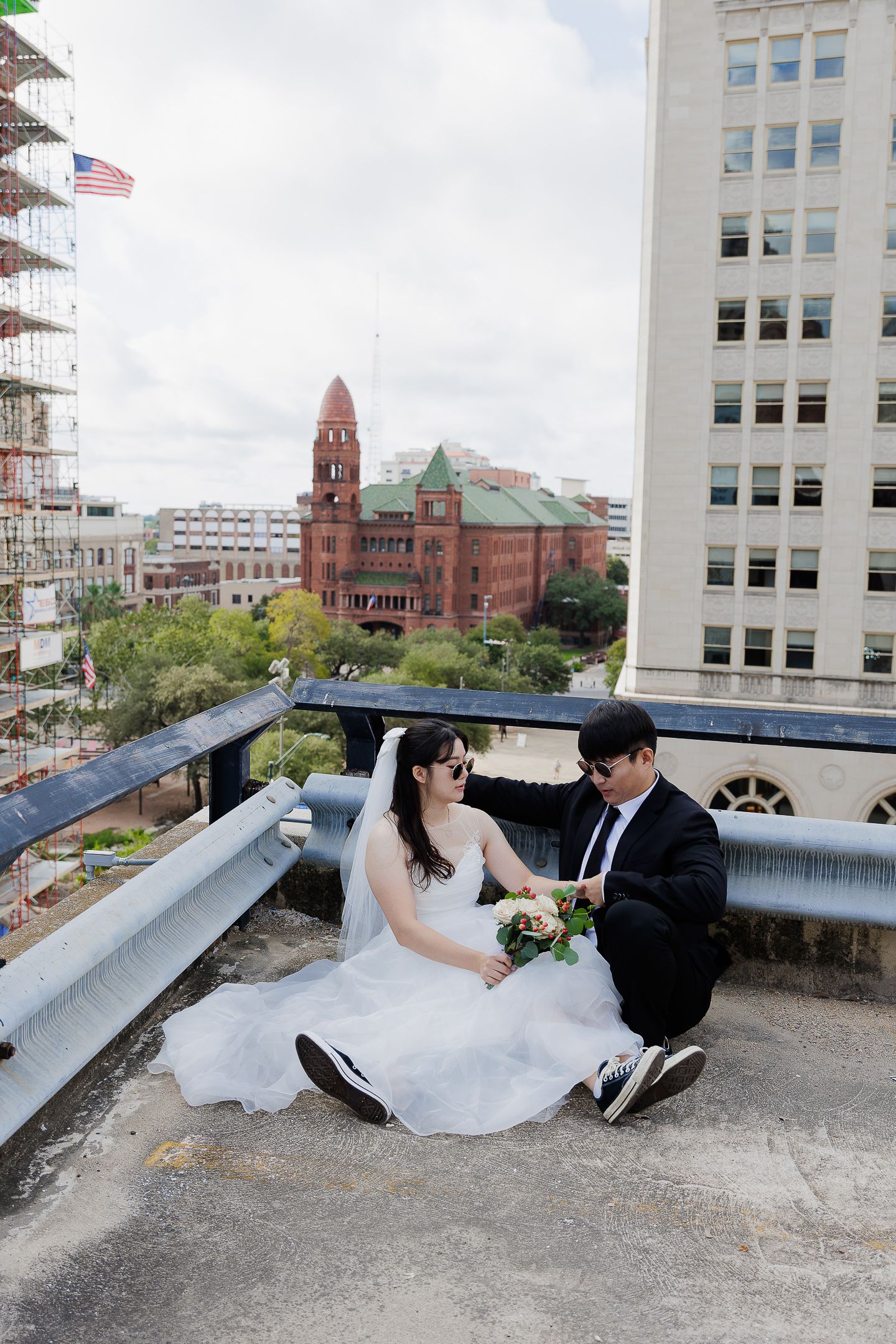 A romantic rooftop wedding photo session with a couple posing against a cityscape backdrop with historic buildings and church spires.