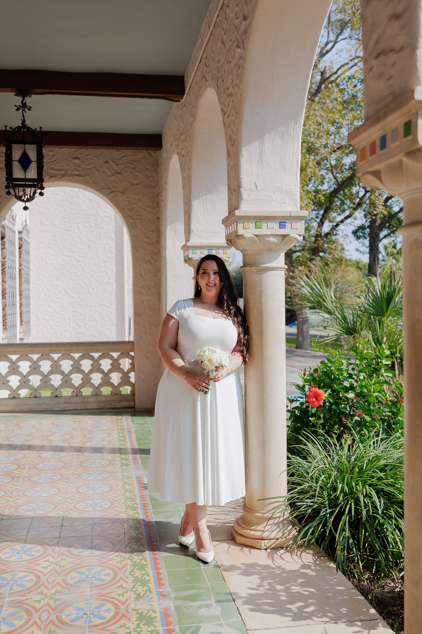 A series of connected photos showing someone in a white dress posing under Mediterranean-style arched columns with tiled floors.