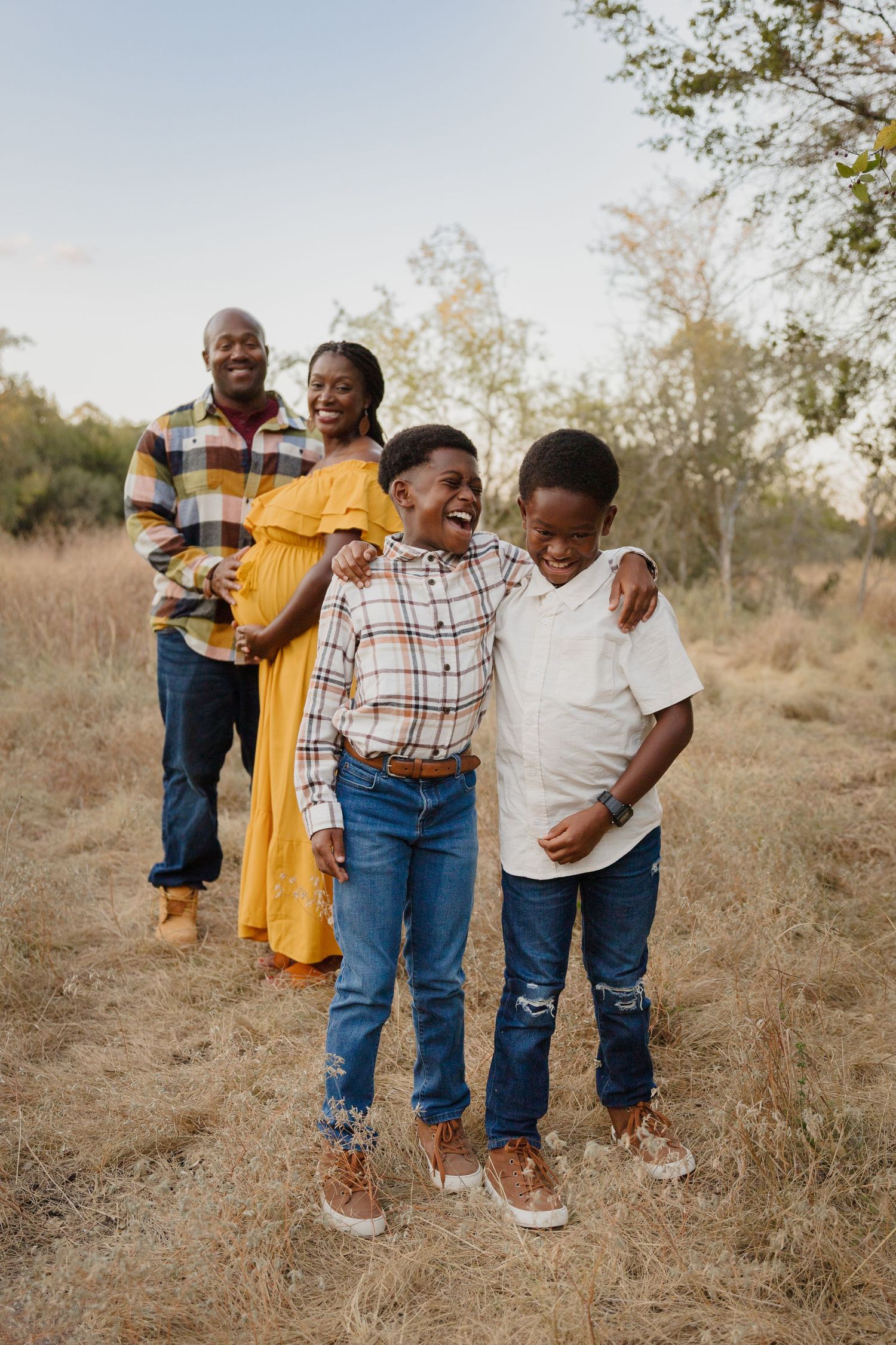 Family of four sharing laughs during outdoor photo session.