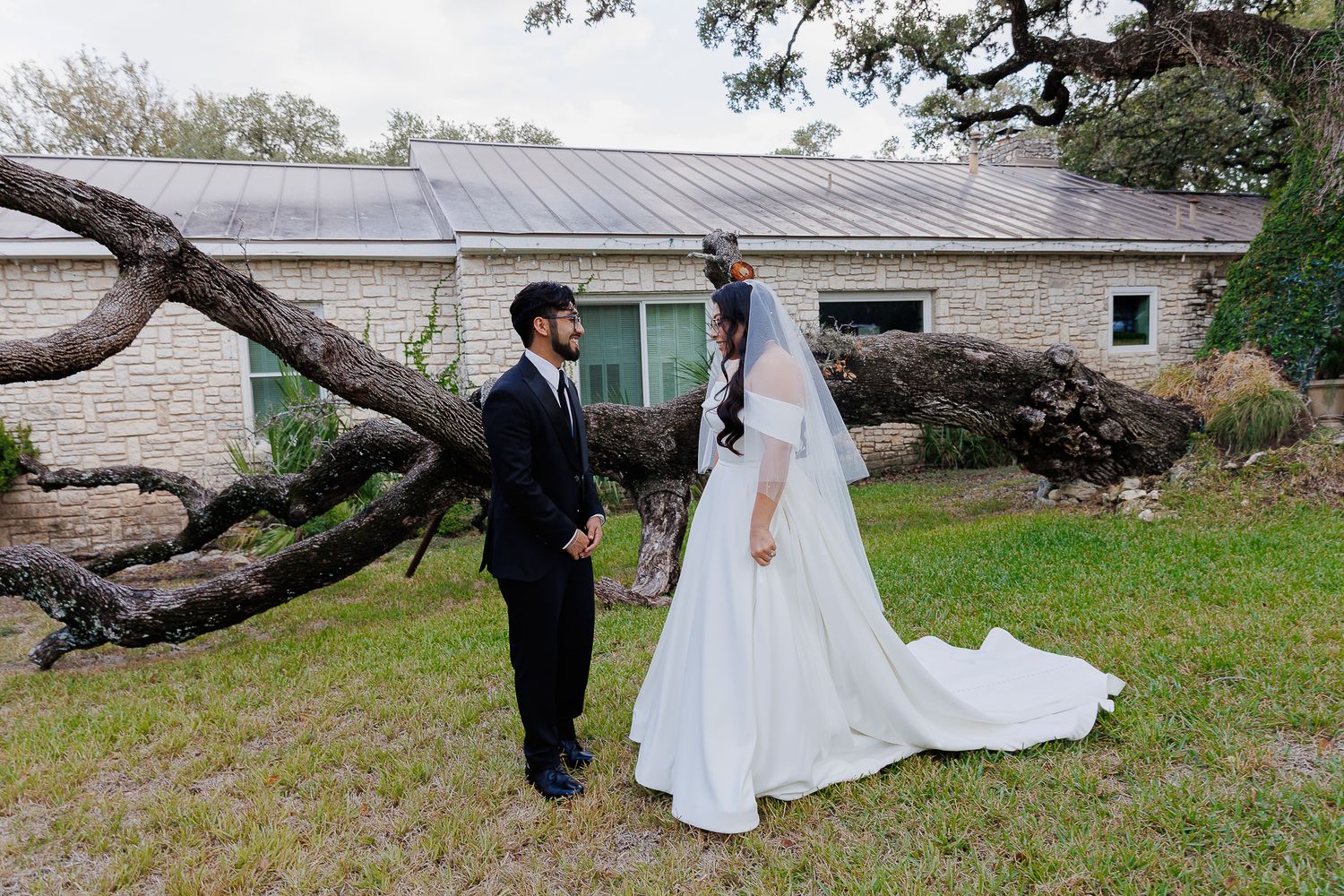 A couple in wedding attire playfully poses in a series of photos under a large tree branch in a garden setting.