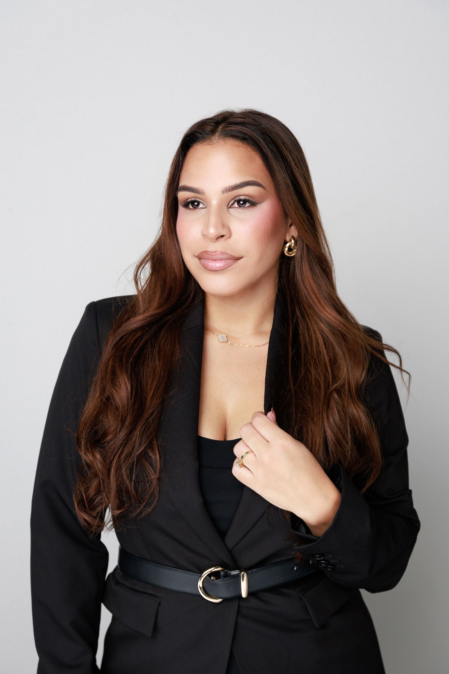 Professional studio portrait series showing a model in a black blazer and dark hair posing against a light background.