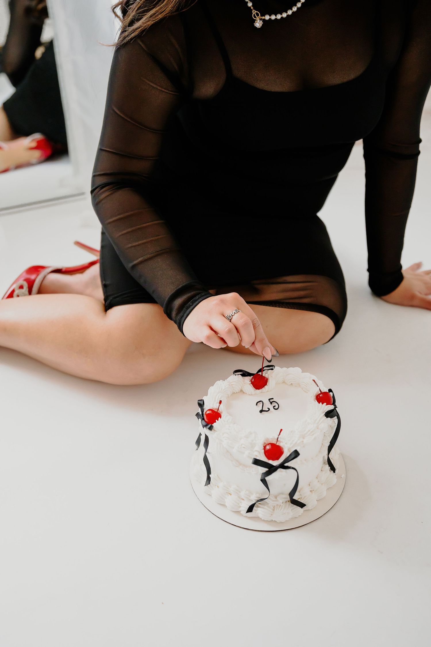 A decorative white cake with red dancing figures sits on a white surface.