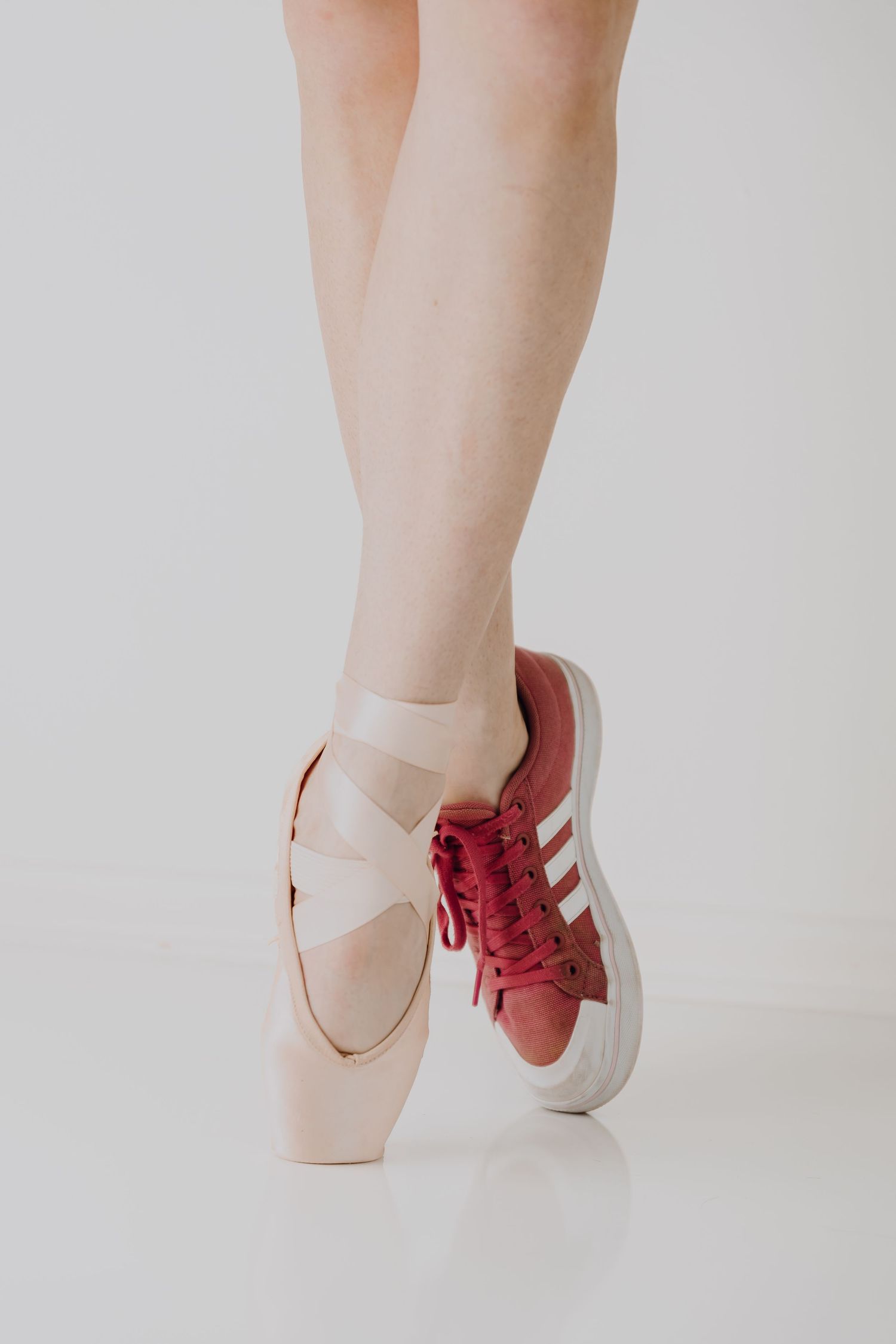 A split image showing a pointe shoe and red sneaker contrasting classical ballet with modern style.