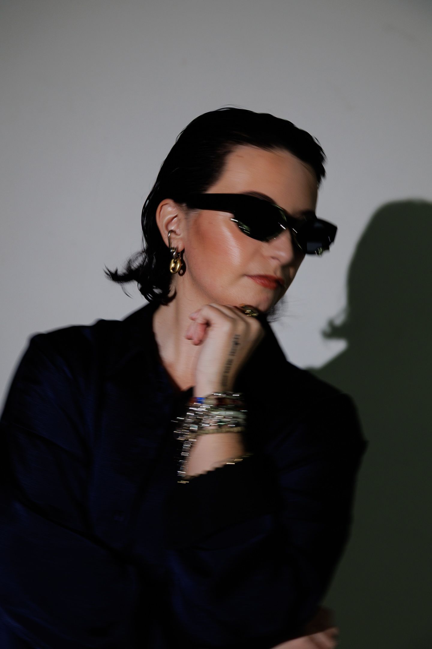 A series of moody profile portraits in dark lighting showing dramatic shadows and movement against a plain background.