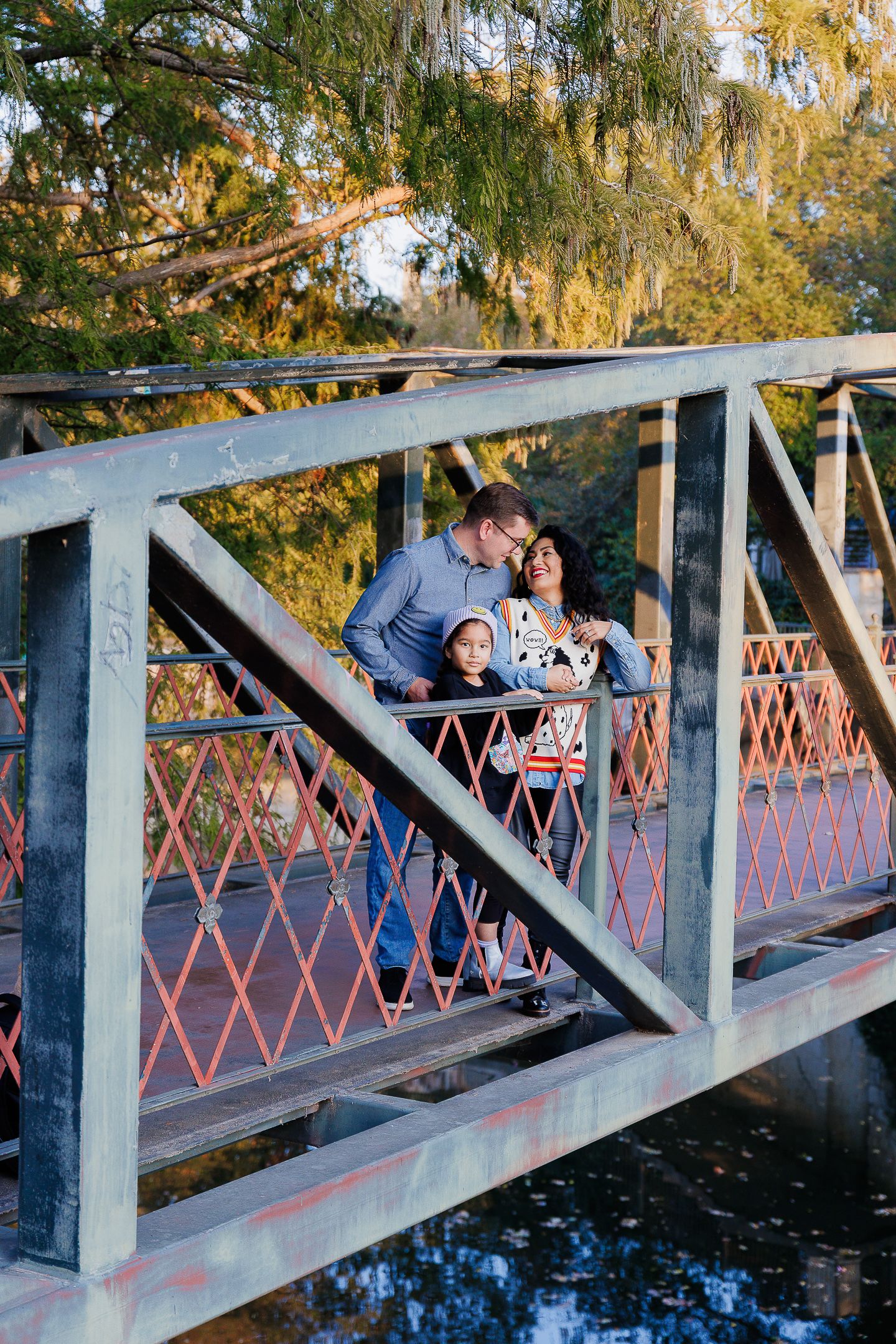 A romantic moment shared on a wooden bridge over water with autumn trees in the background.