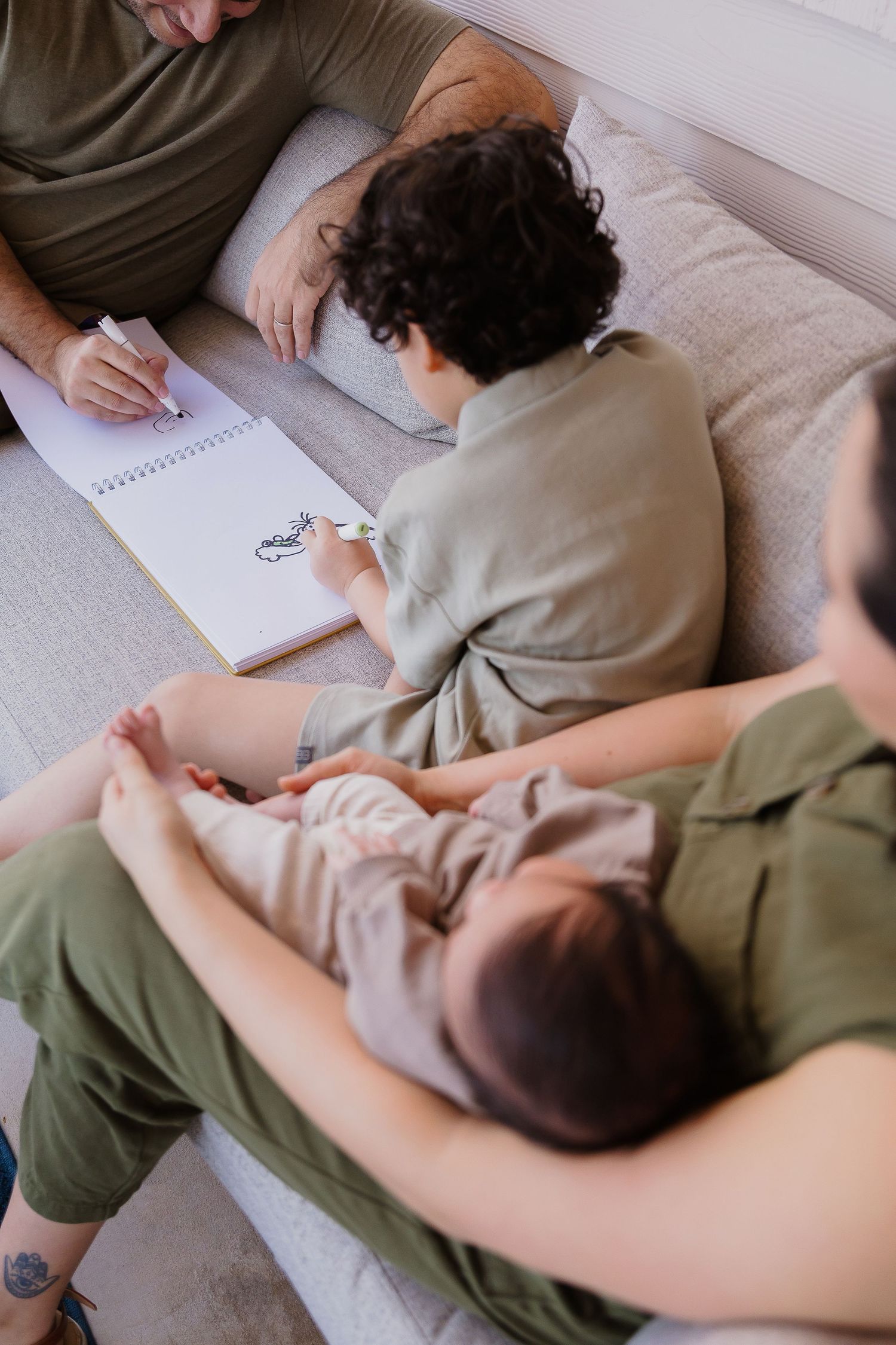 Small group relaxing together on a couch while sketching in a notebook.