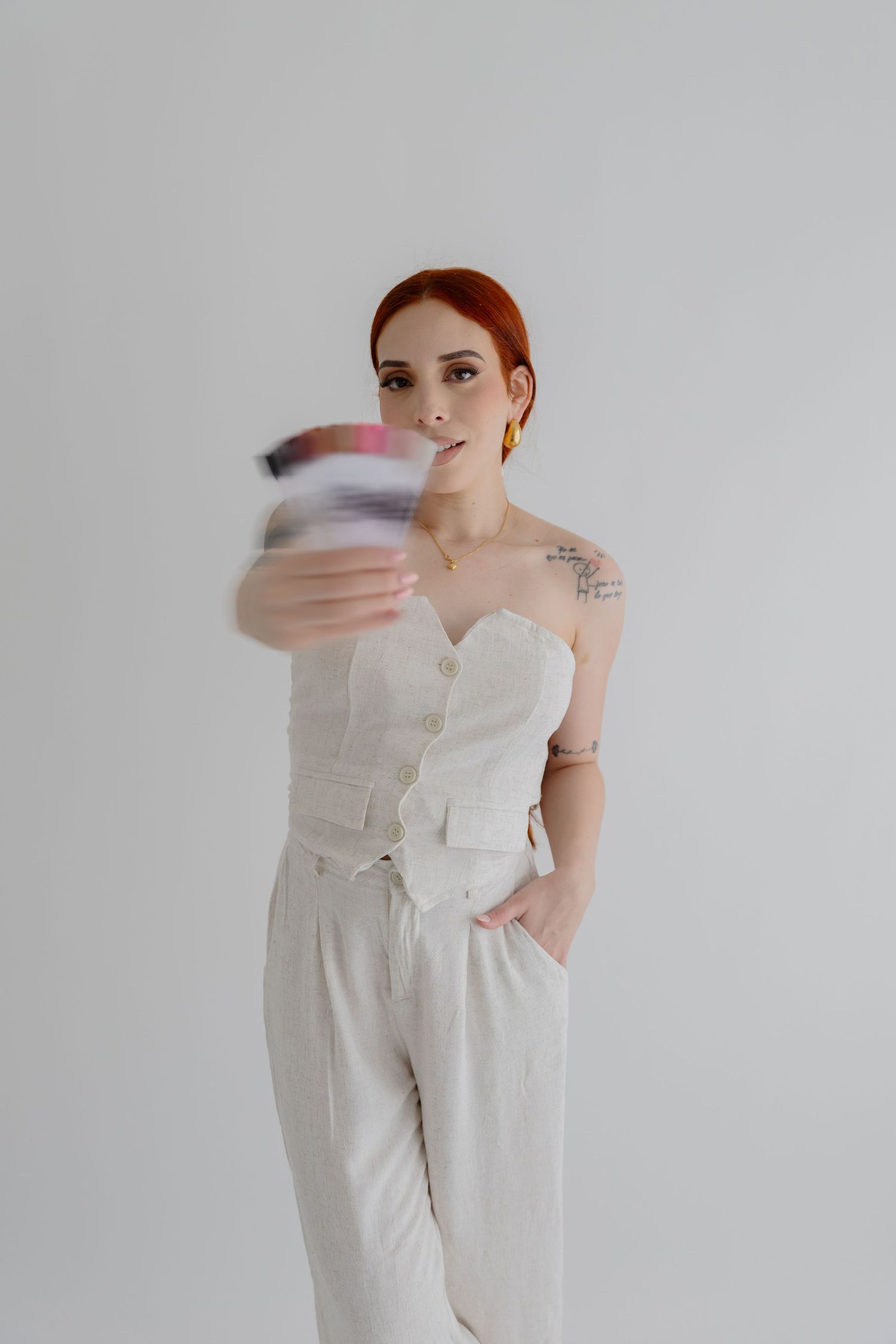 Woman in white outfit creating motion blur with colorful object in studio setting.