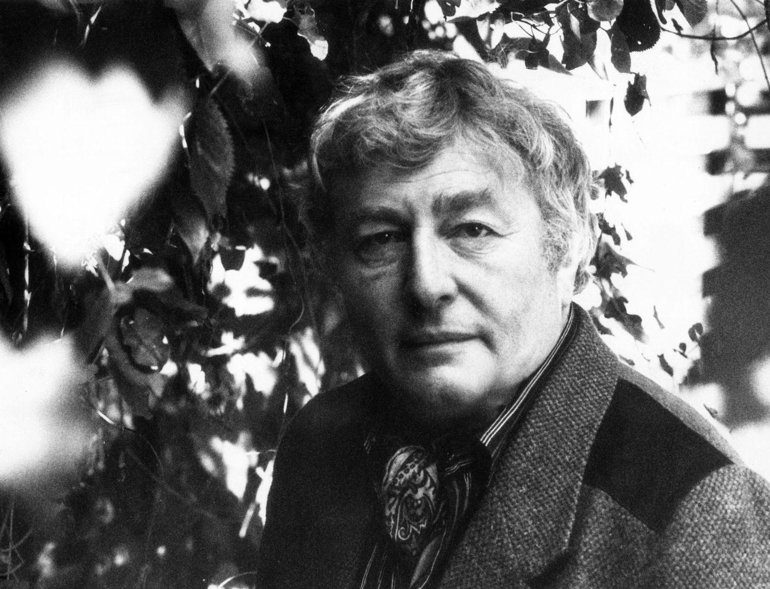 Vintage black and white portrait of older man in tweed jacket outdoors.