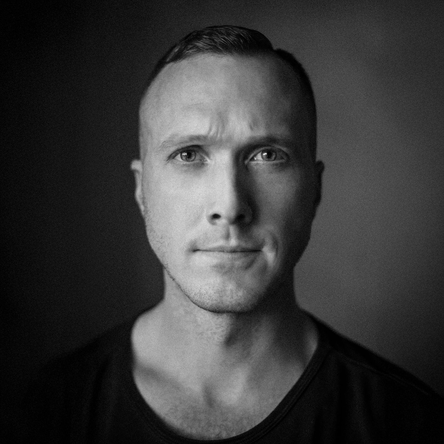 Black and white close-up portrait of person in dark shirt.