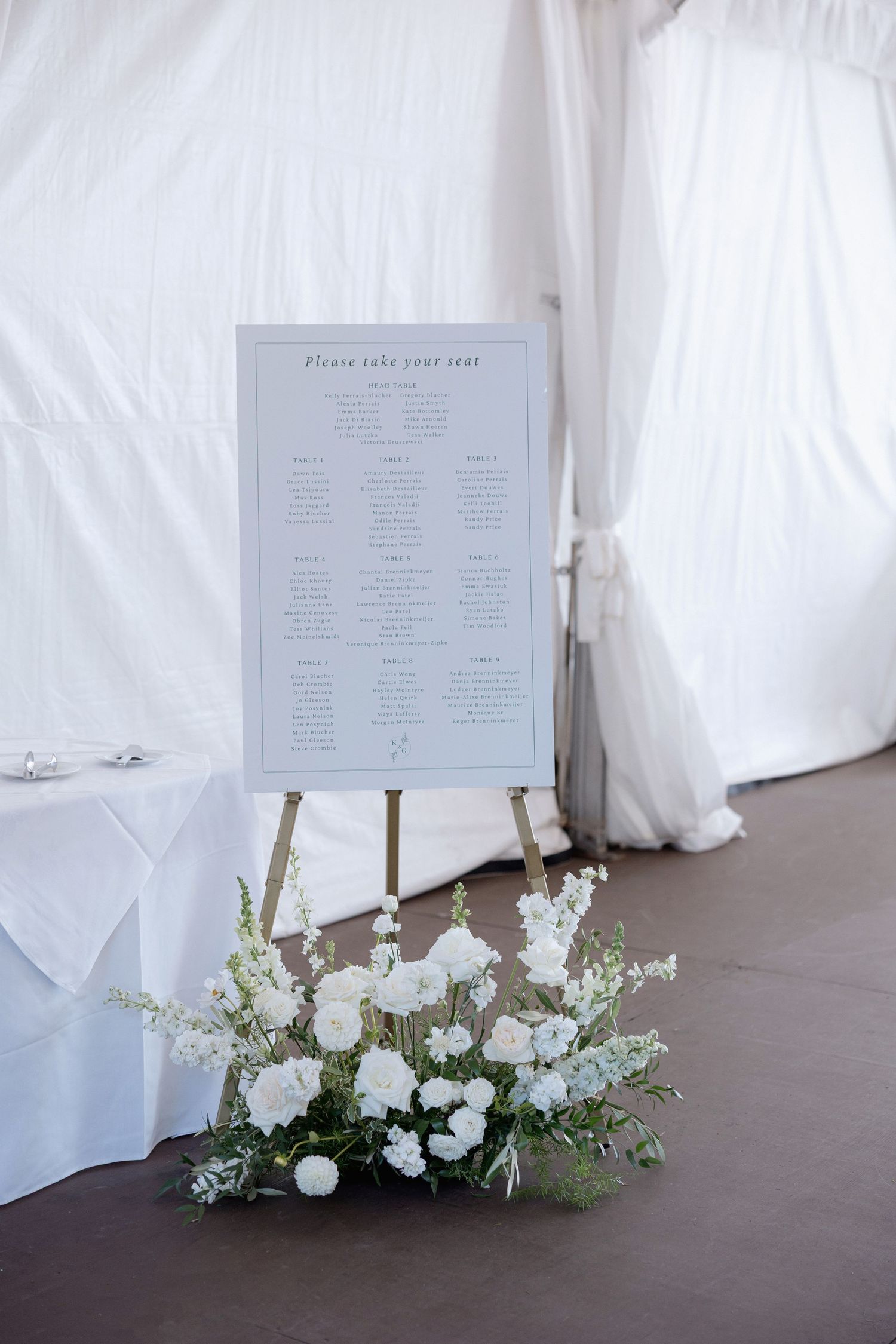White floral seating chart display with fresh flower arrangements at the base.