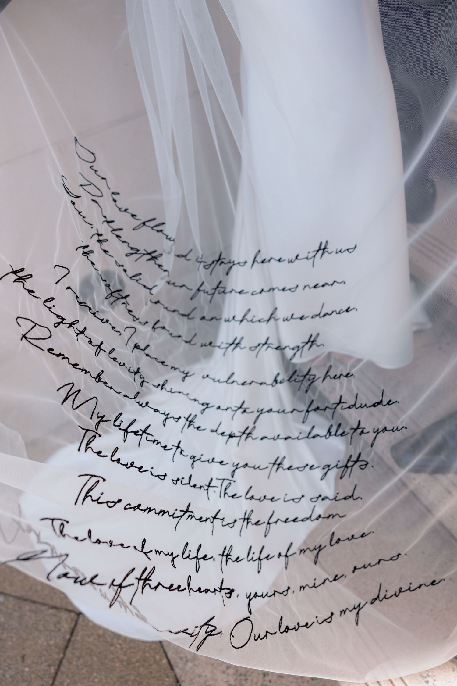 Handwritten text in black ink on white wedding dress fabric.