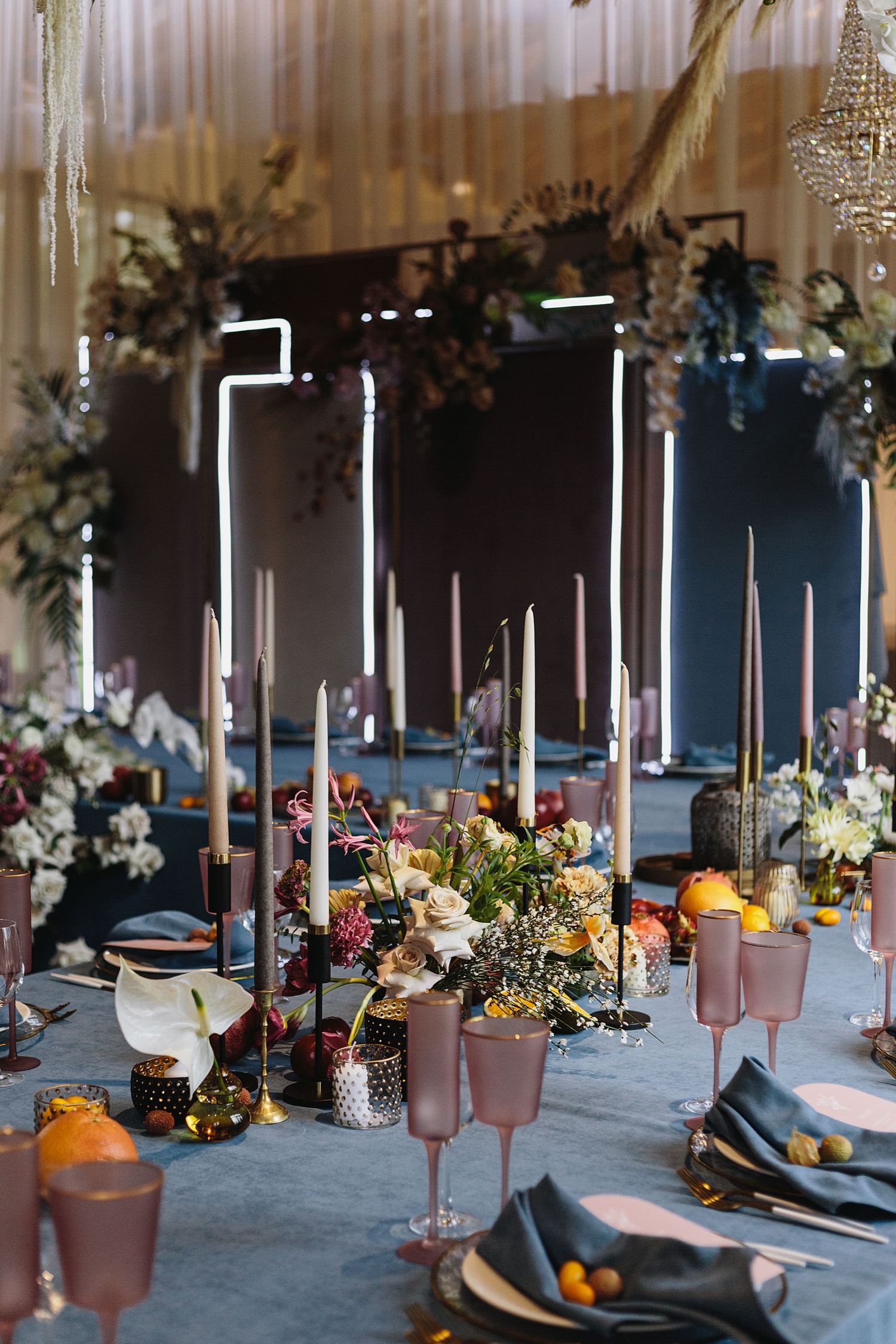 Elegant wedding table setting with pink glassware, candles, and citrus accents.