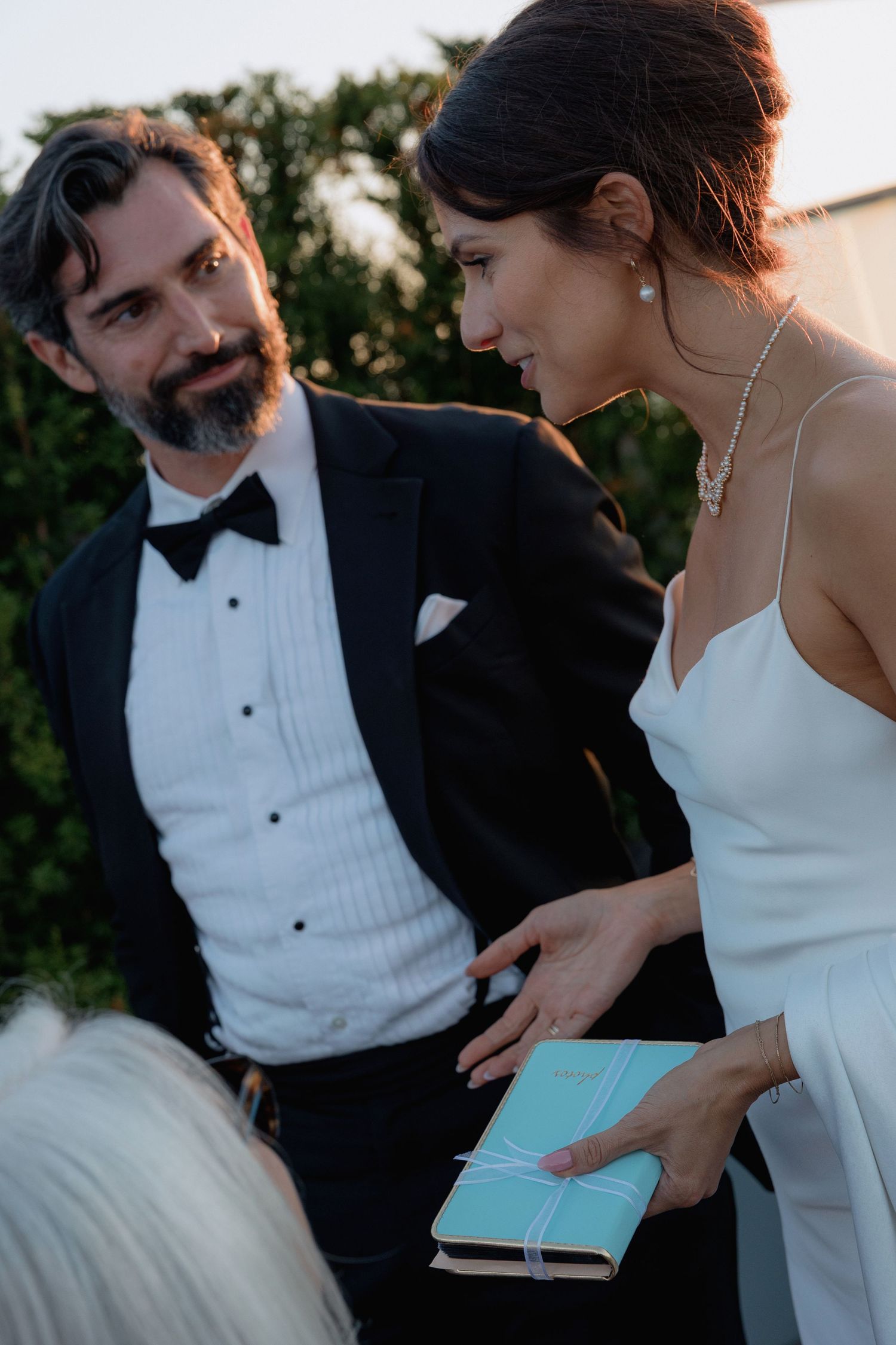 A couple shares an intimate moment at a formal event, with the bride holding a turquoise book.