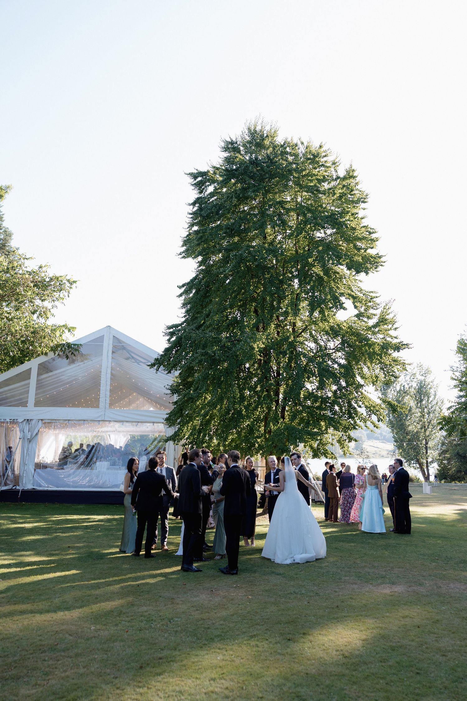 Wedding celebration under a white tent with guests mingling on a manicured lawn in Hurt House in Burnaby