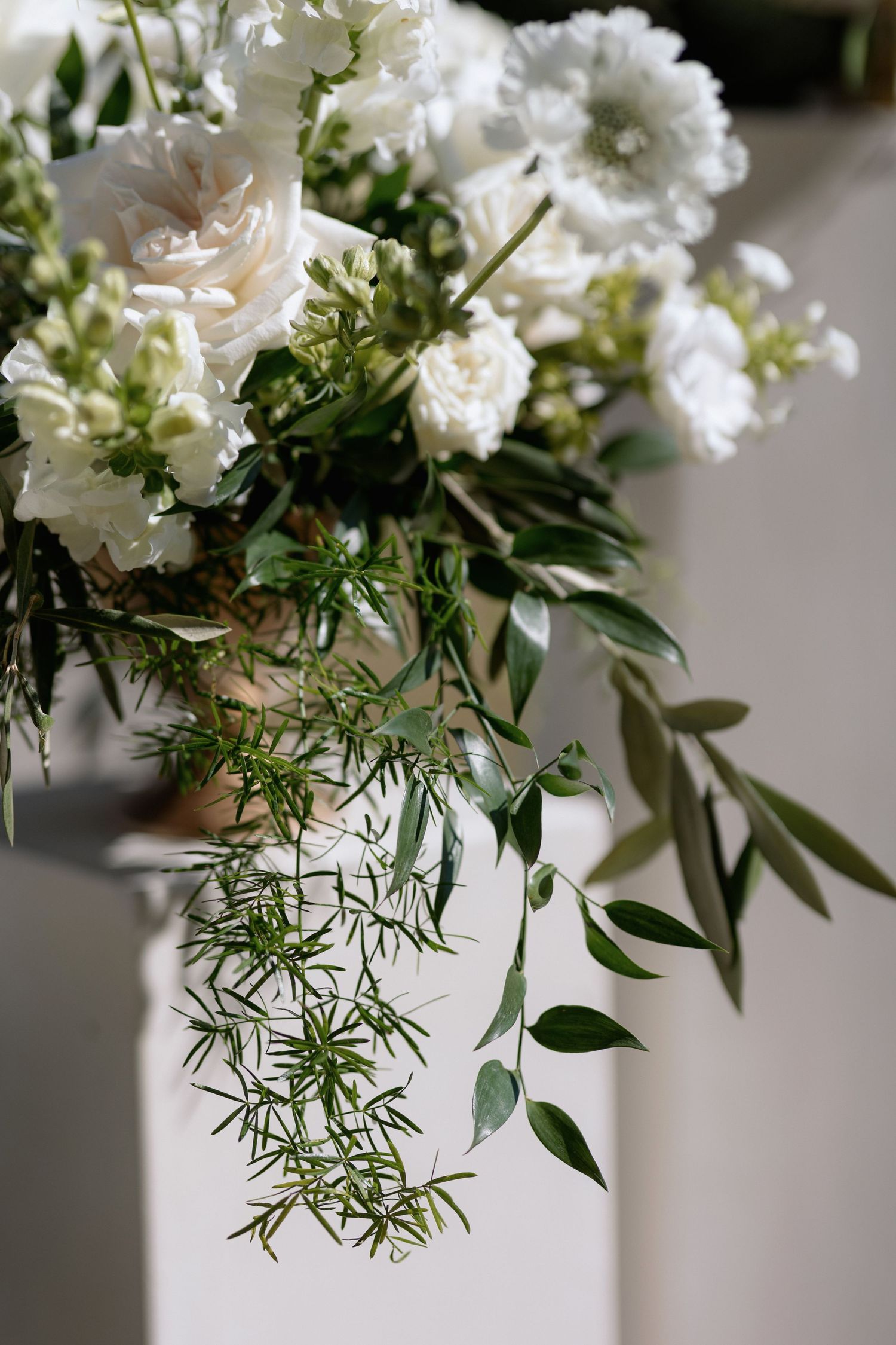 Close-up of white floral arrangements with delicate greenery and roses.
