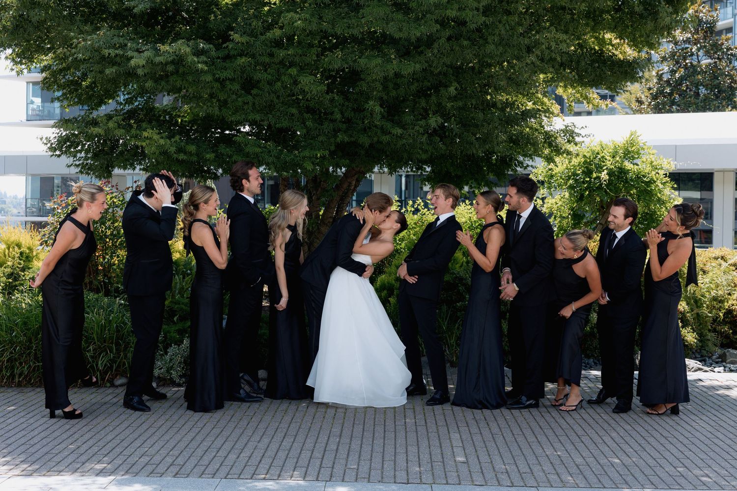 Wedding party poses creatively outdoors with greenery and modern architecture at Marriott Hotel in Vancouver
