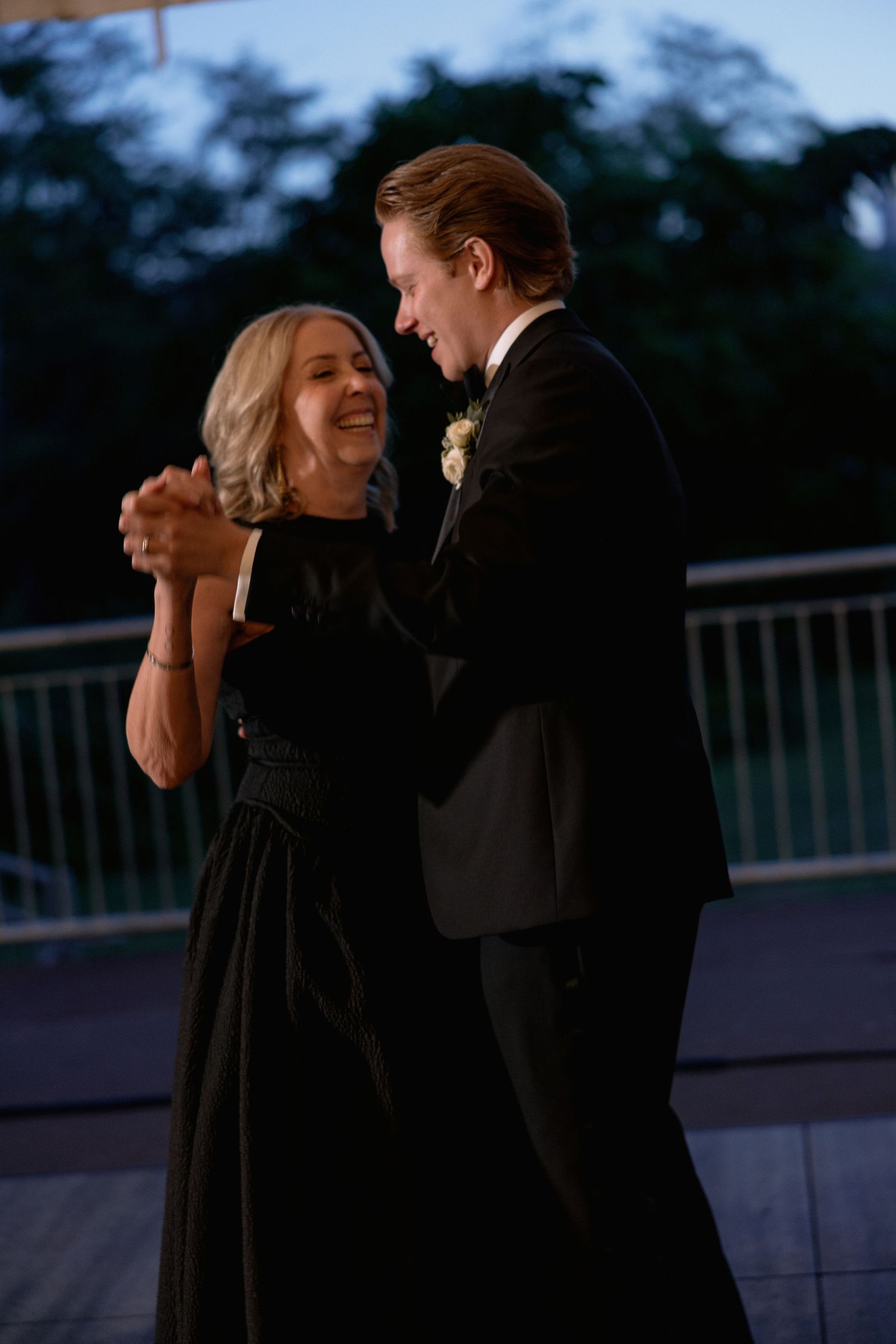 Joyful dance partners sharing a laugh during an evening reception on an outdoor terrace.
