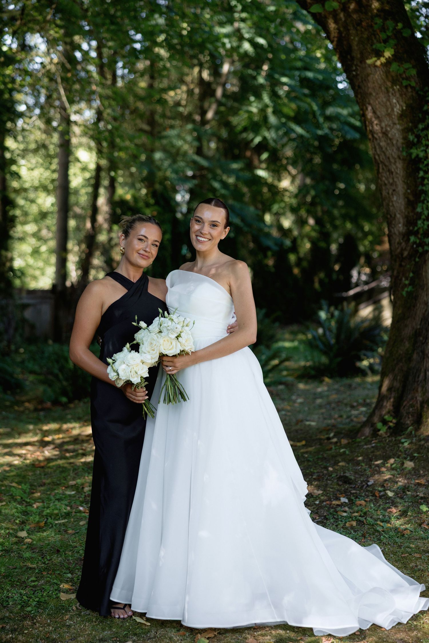 Forest wedding portrait featuring two people in complementary black and white dresses.