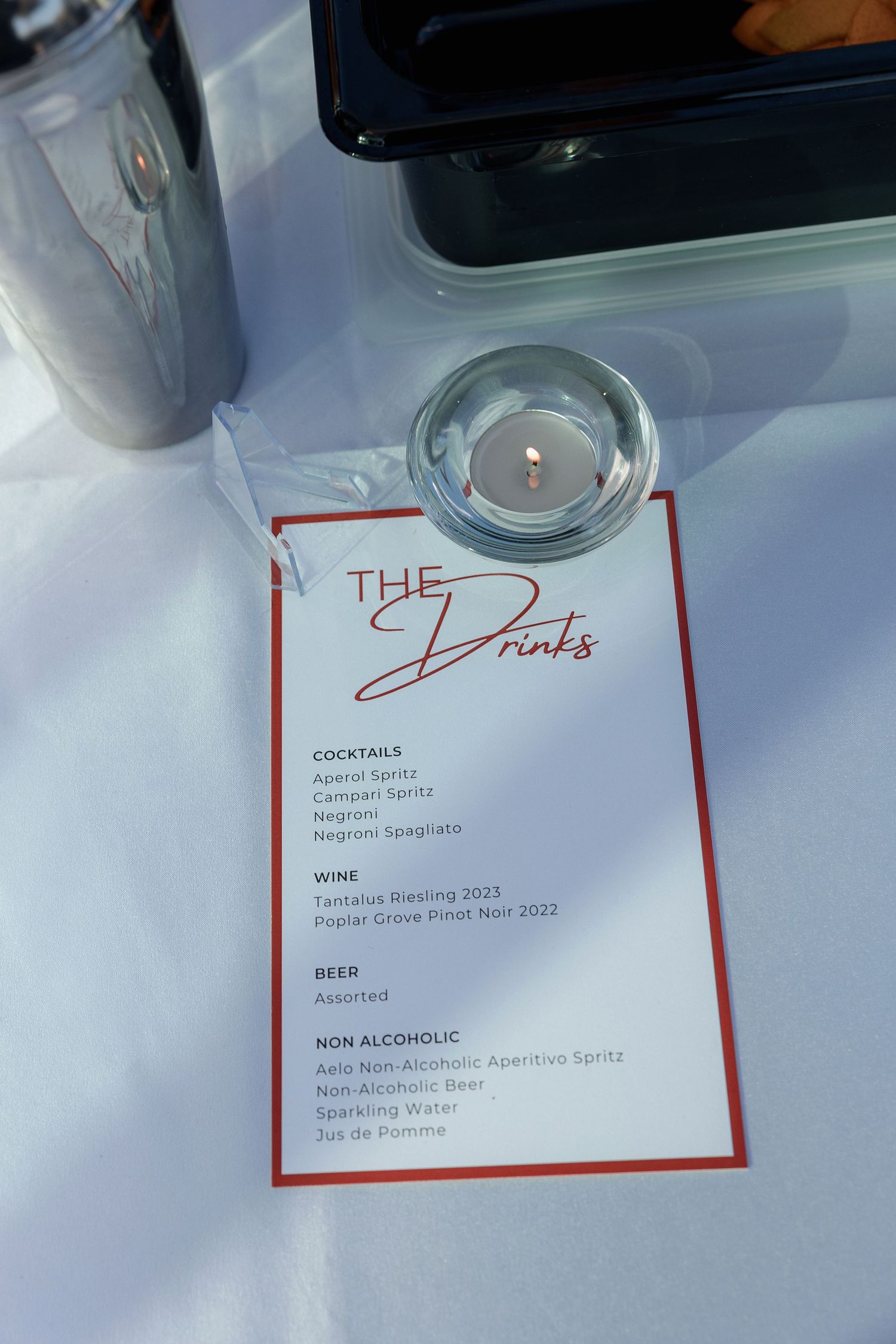 Restaurant menu pages with red borders showing drink selections including wine and non-alcoholic options on a white surface.