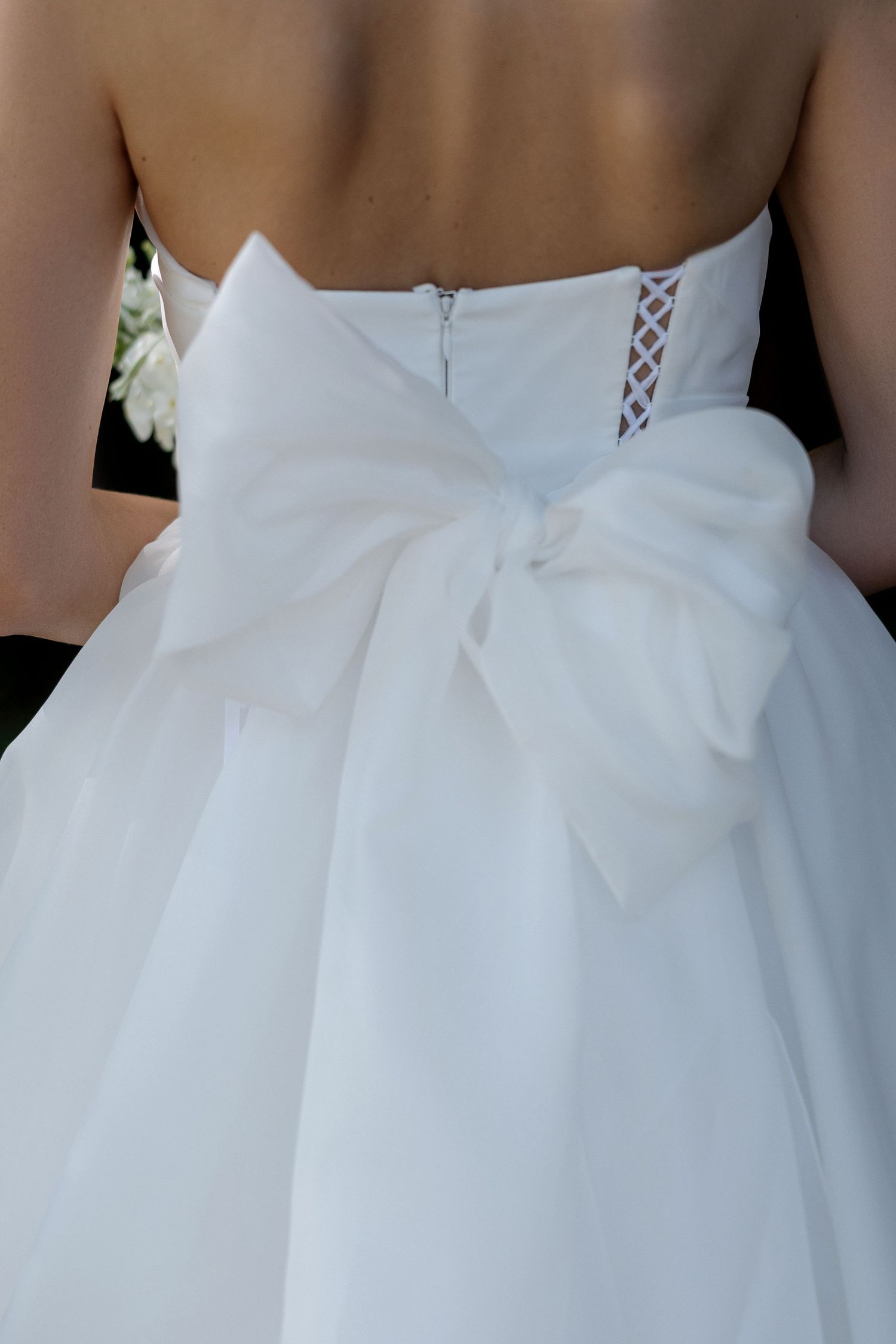Close-up details of a white wedding dress showing intricate lace-up corset back design.
