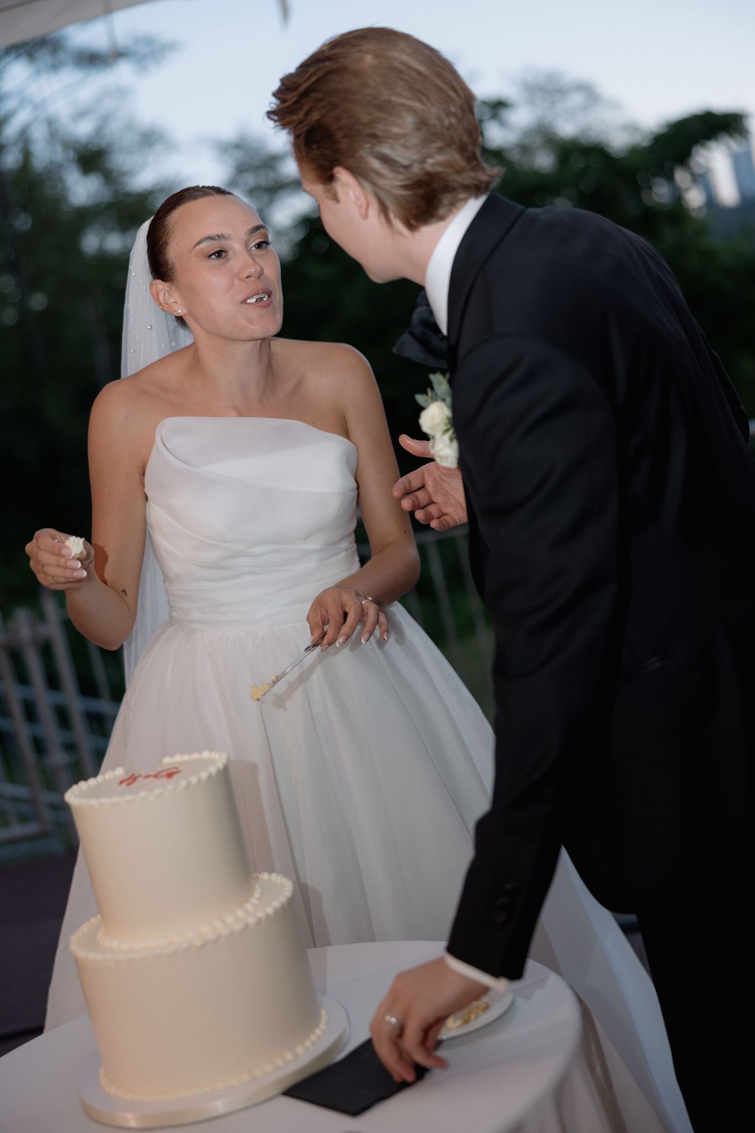 A candid moment of newlyweds laughing during their cake-cutting ceremony.