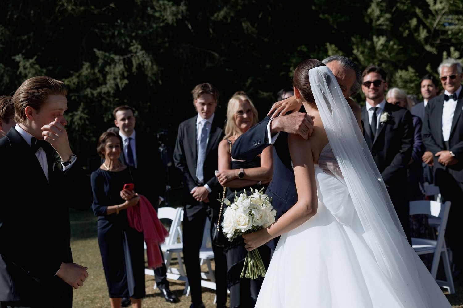 Wedding celebration in a garden setting with guests watching the ceremony proceedings.
