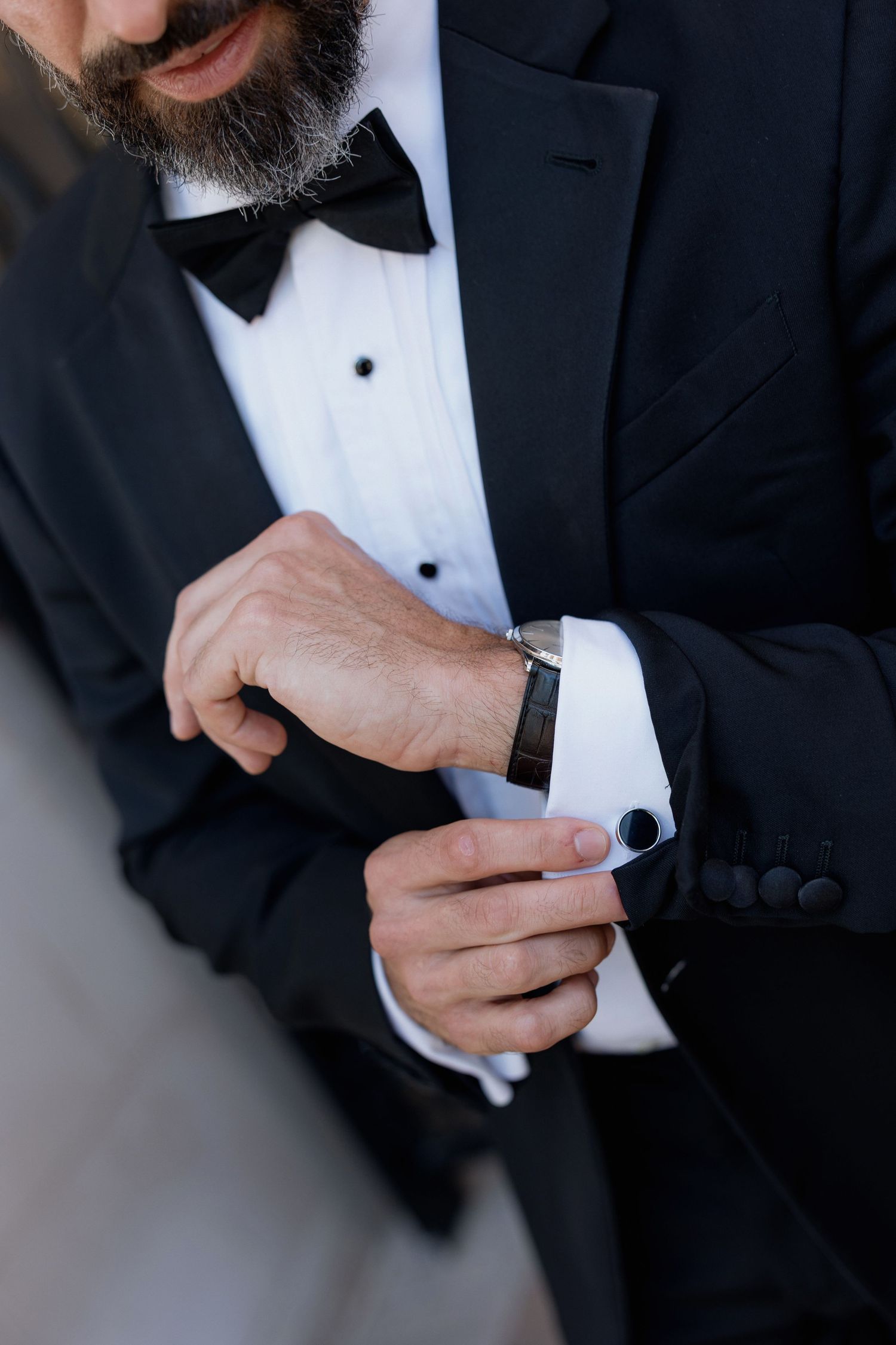 Detail shot of tuxedo with black bow tie and cufflinks being adjusted.