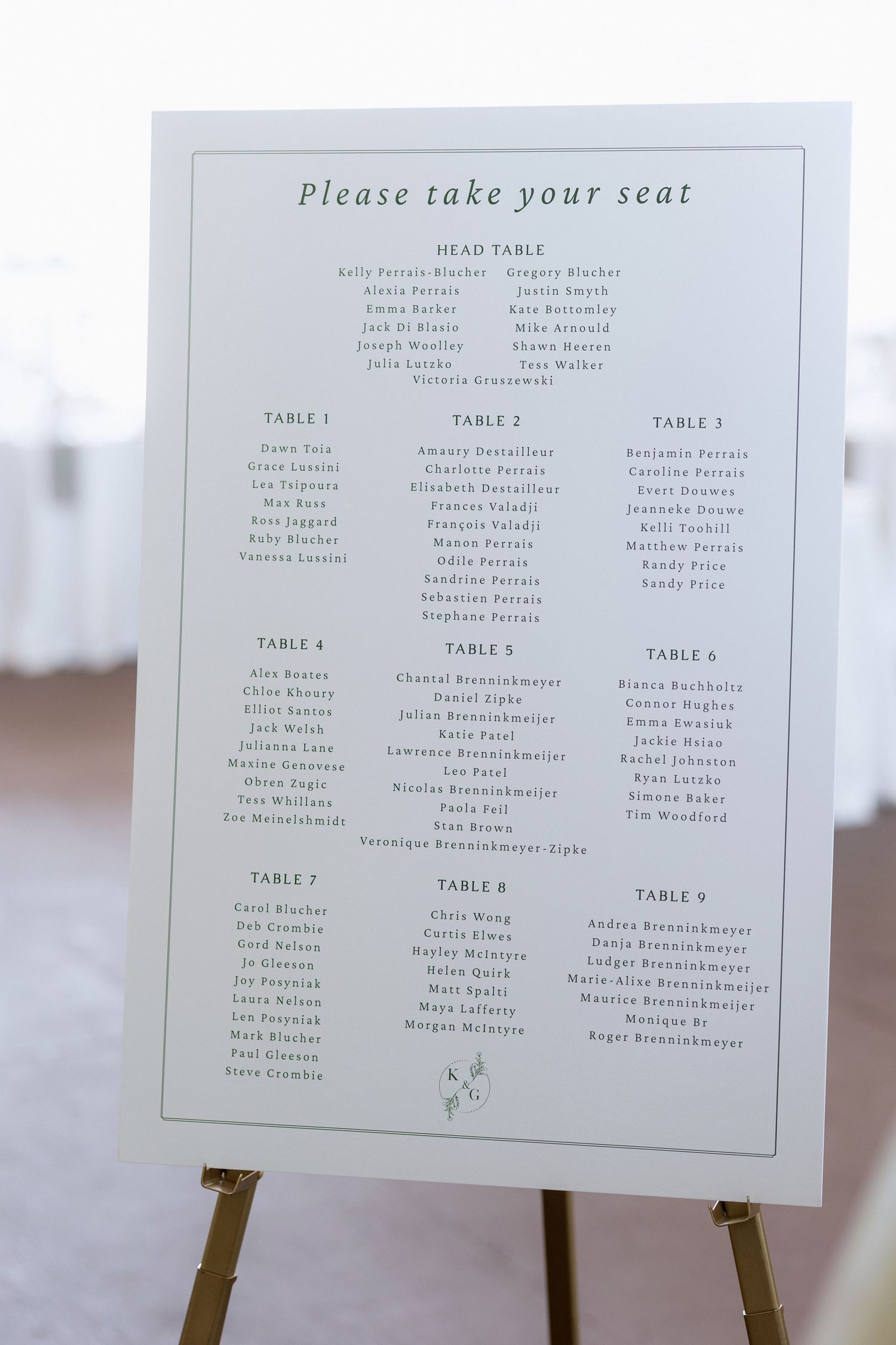 Wedding seating chart displayed on white easel showing table assignments.