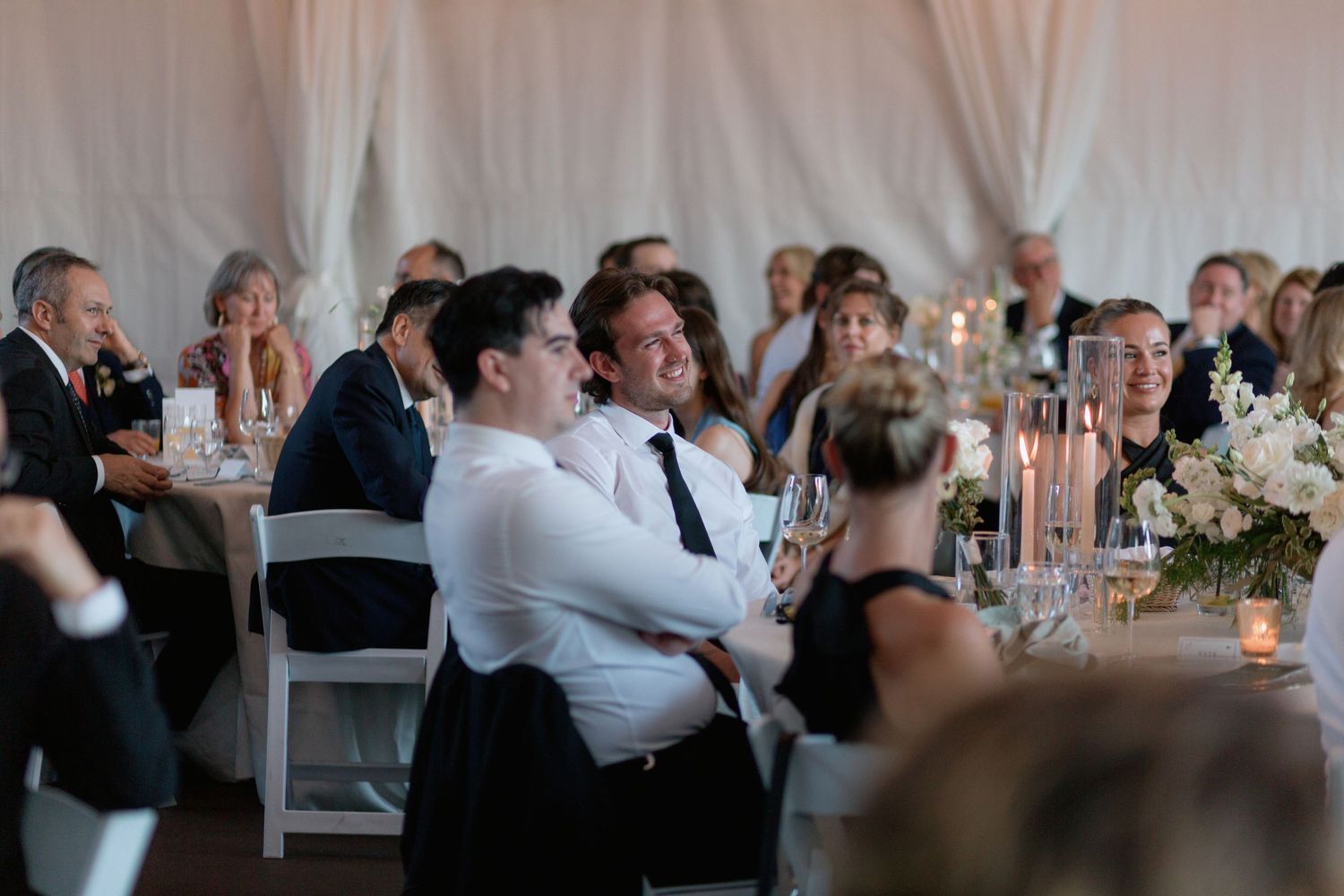 Wedding reception guests seated at long tables during evening celebration.