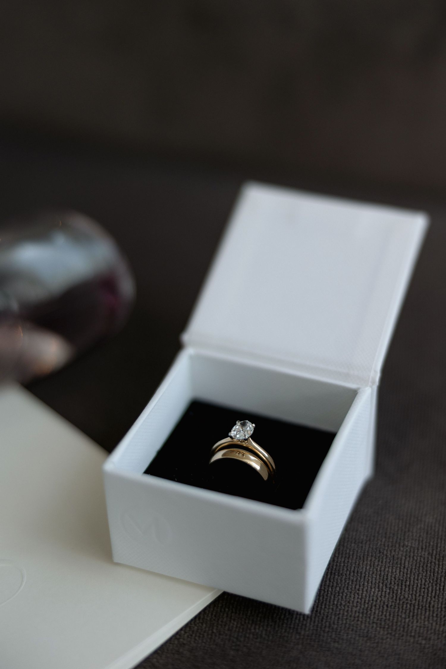 A diamond engagement ring sits in an elegant white jewelry box.