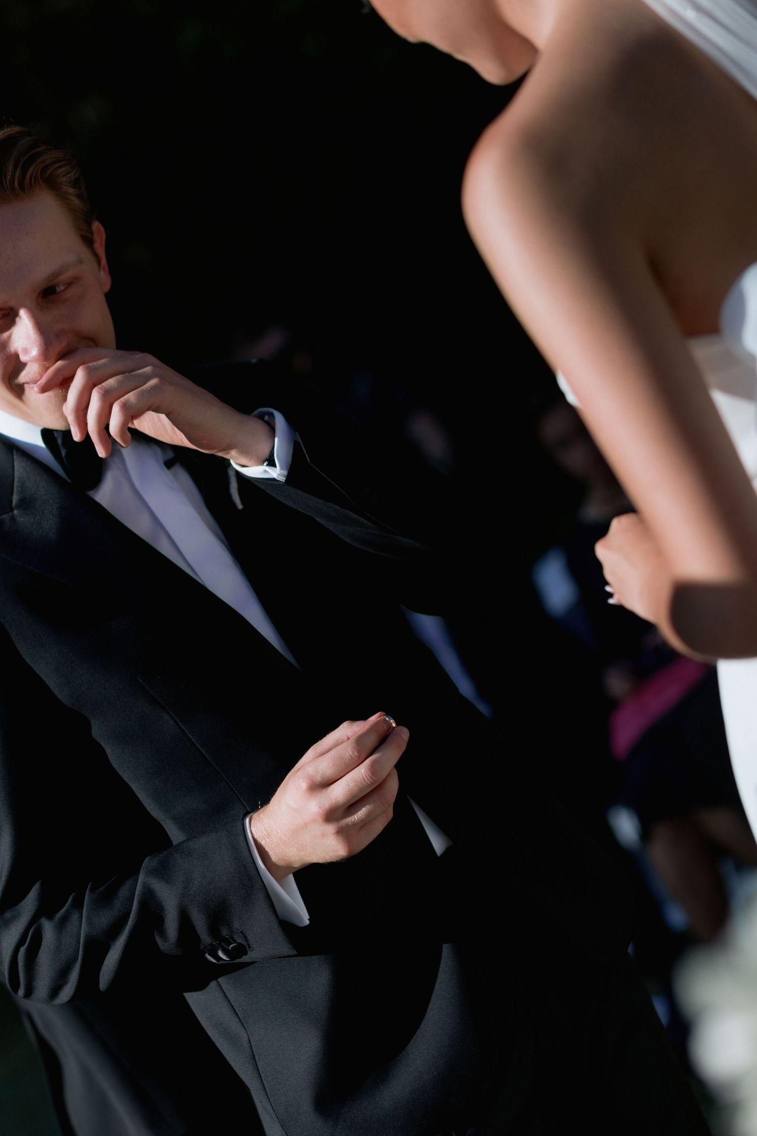 Wedding attendees in formal attire share emotional reactions during the ceremony.