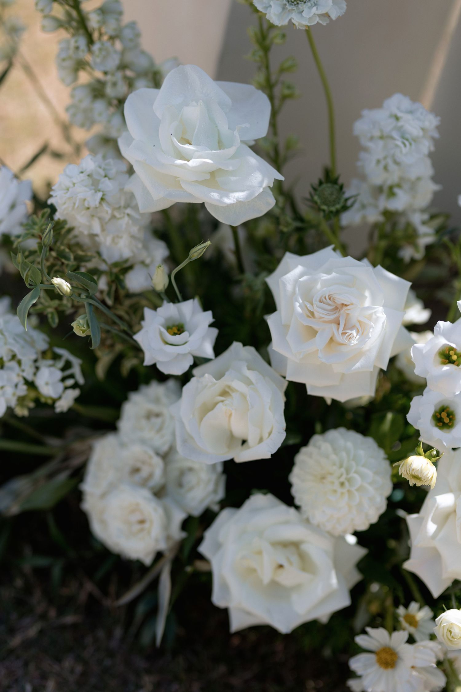 Detailed view of white garden roses and mixed flowers in an elegant arrangement.