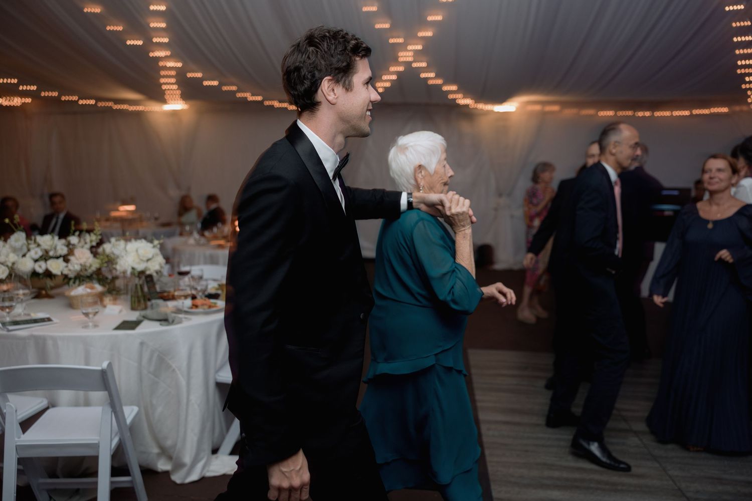 Guests sharing a dance moment at an elegant wedding reception with white table settings.
