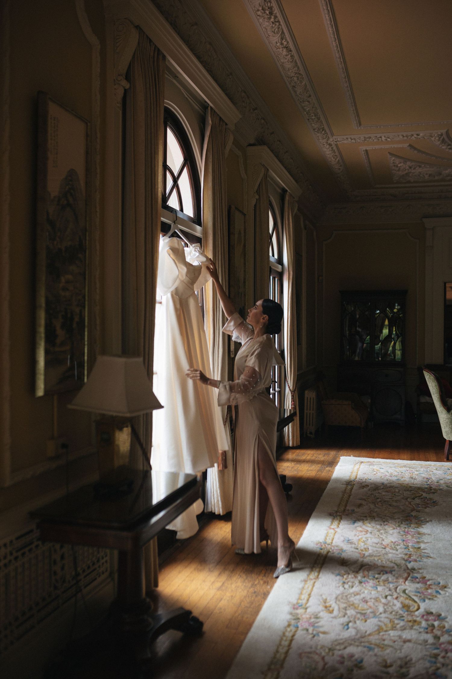 Sunlit hallway with ornate architectural details and flowing curtains creating dramatic shadows.