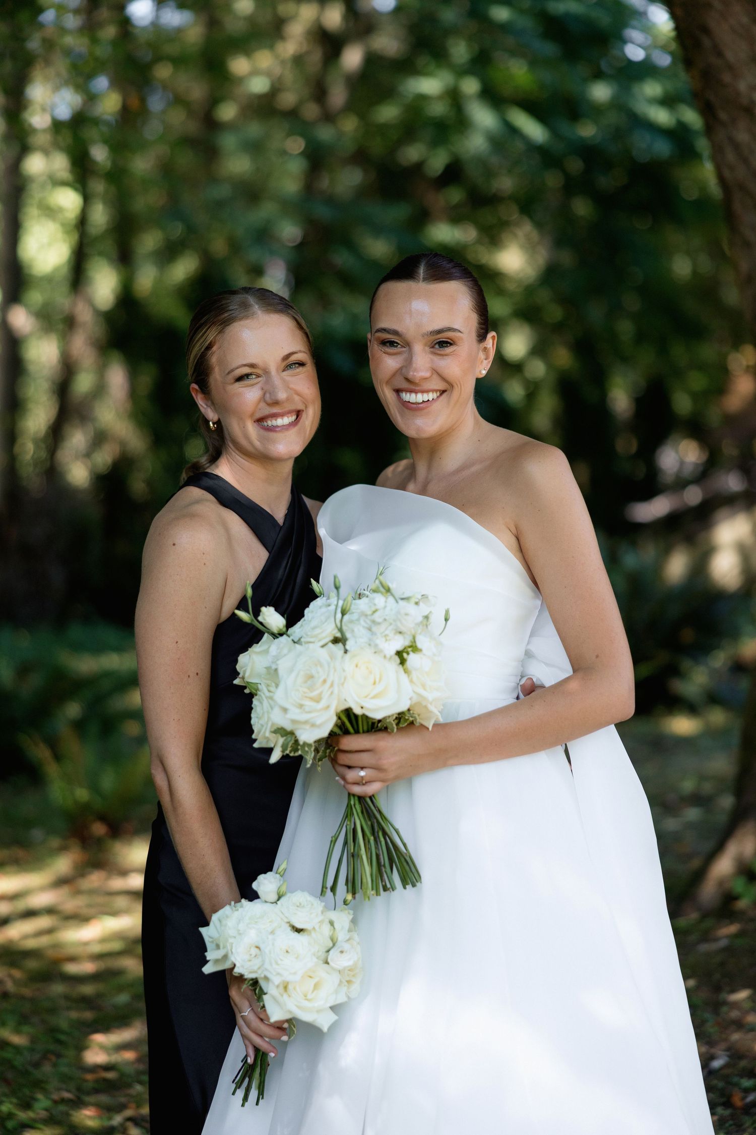 Joyful wedding party members share embraces during outdoor photo session.