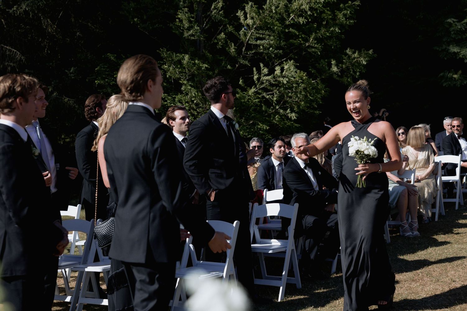 Wedding ceremony setup in a natural setting with guests arriving and mingling.