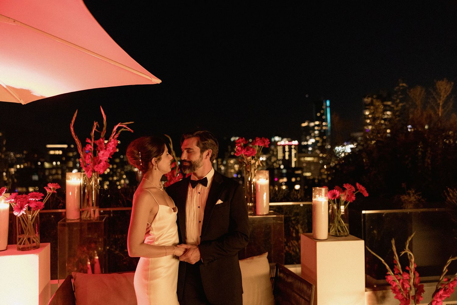 Romantic rooftop wedding reception at night with red lighting and city lights in background in the night of Vancouver