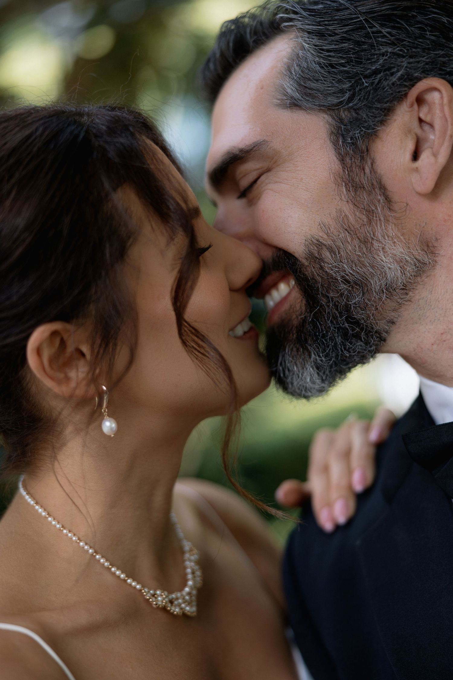 An intimate wedding portrait shows a couple sharing a tender moment in natural outdoor lighting.