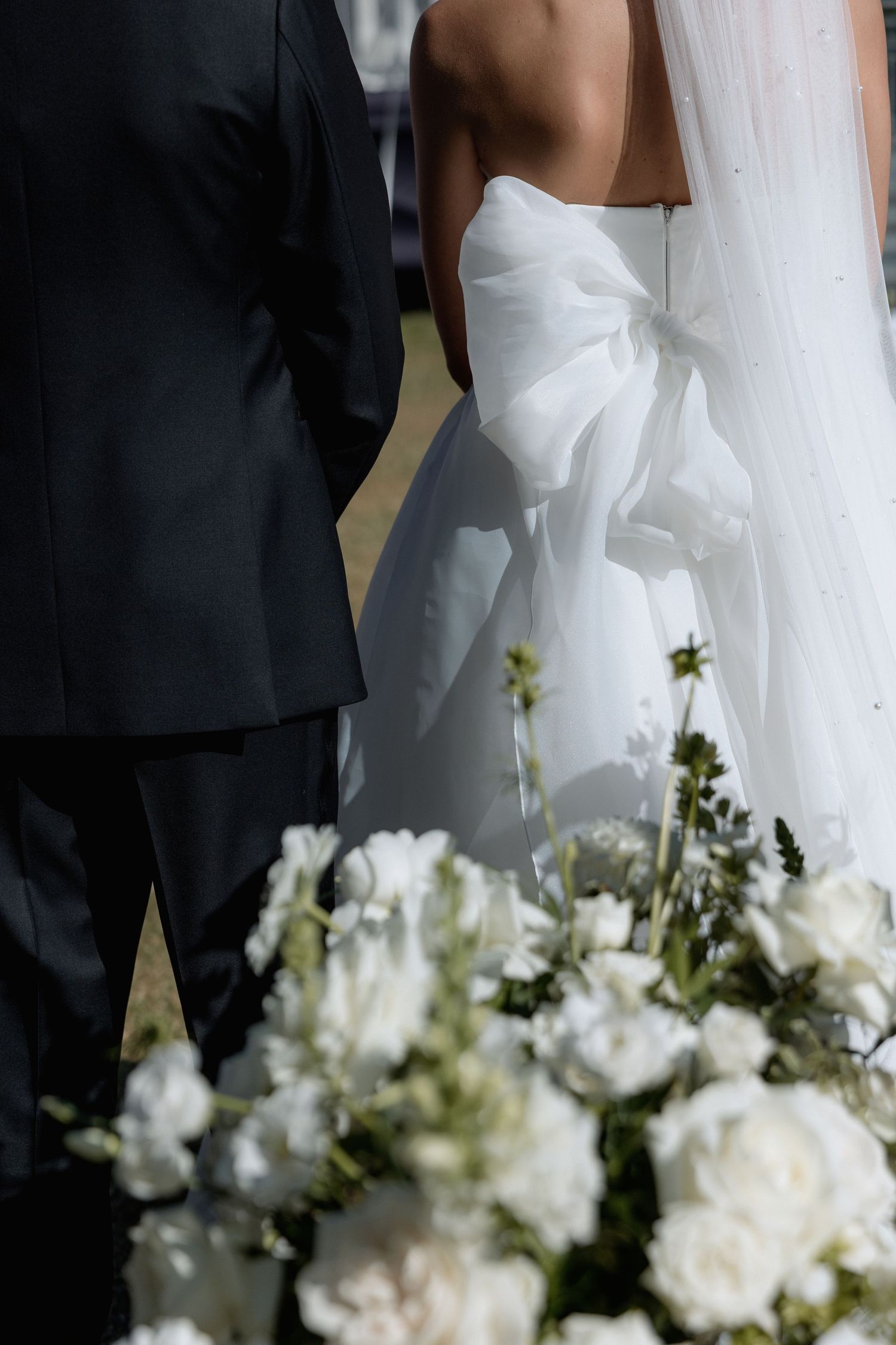 White floral arrangements frame the bottom of a wedding dress.