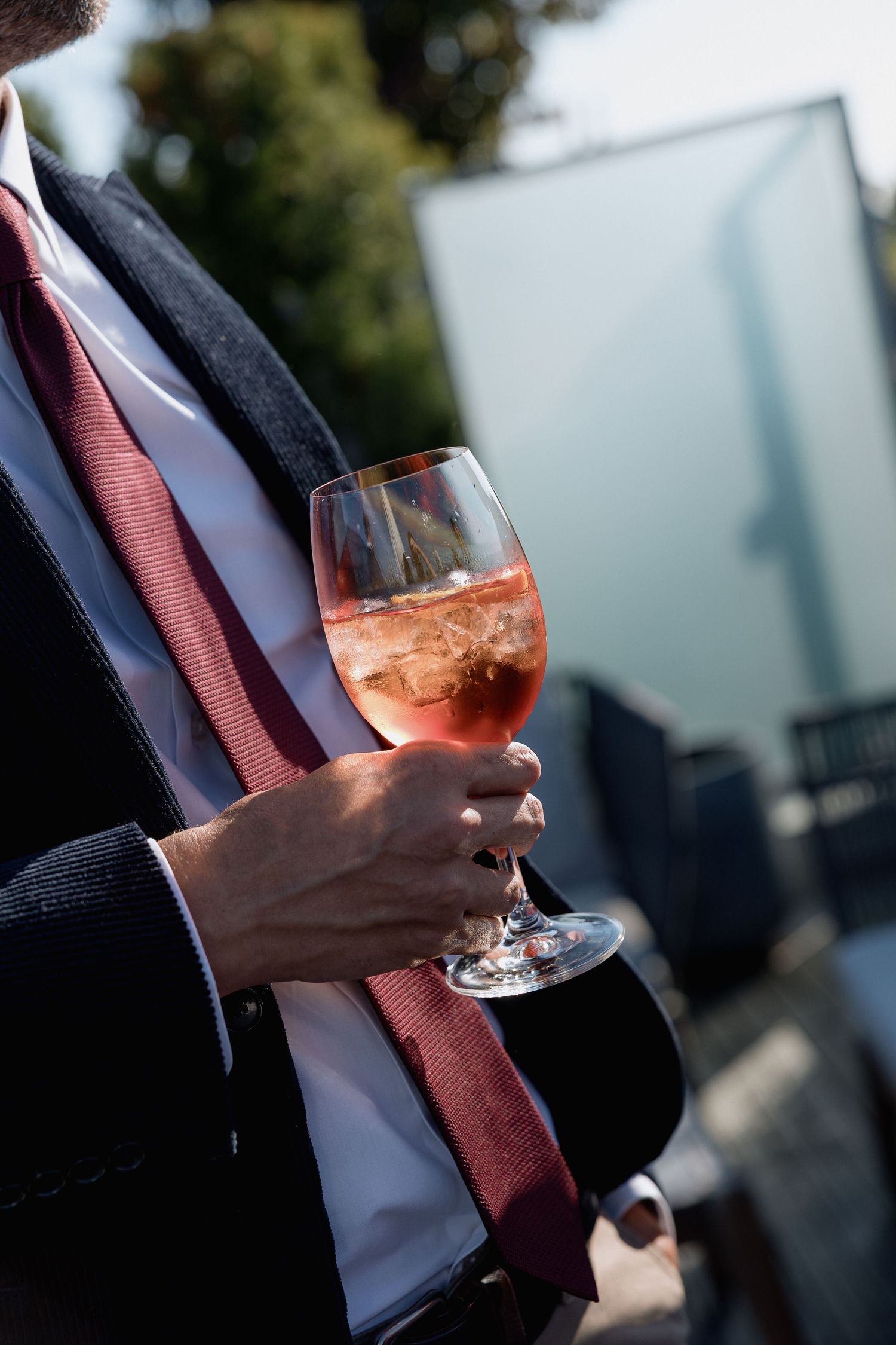 Close-up of hands holding wine glasses during an outdoor celebration.
