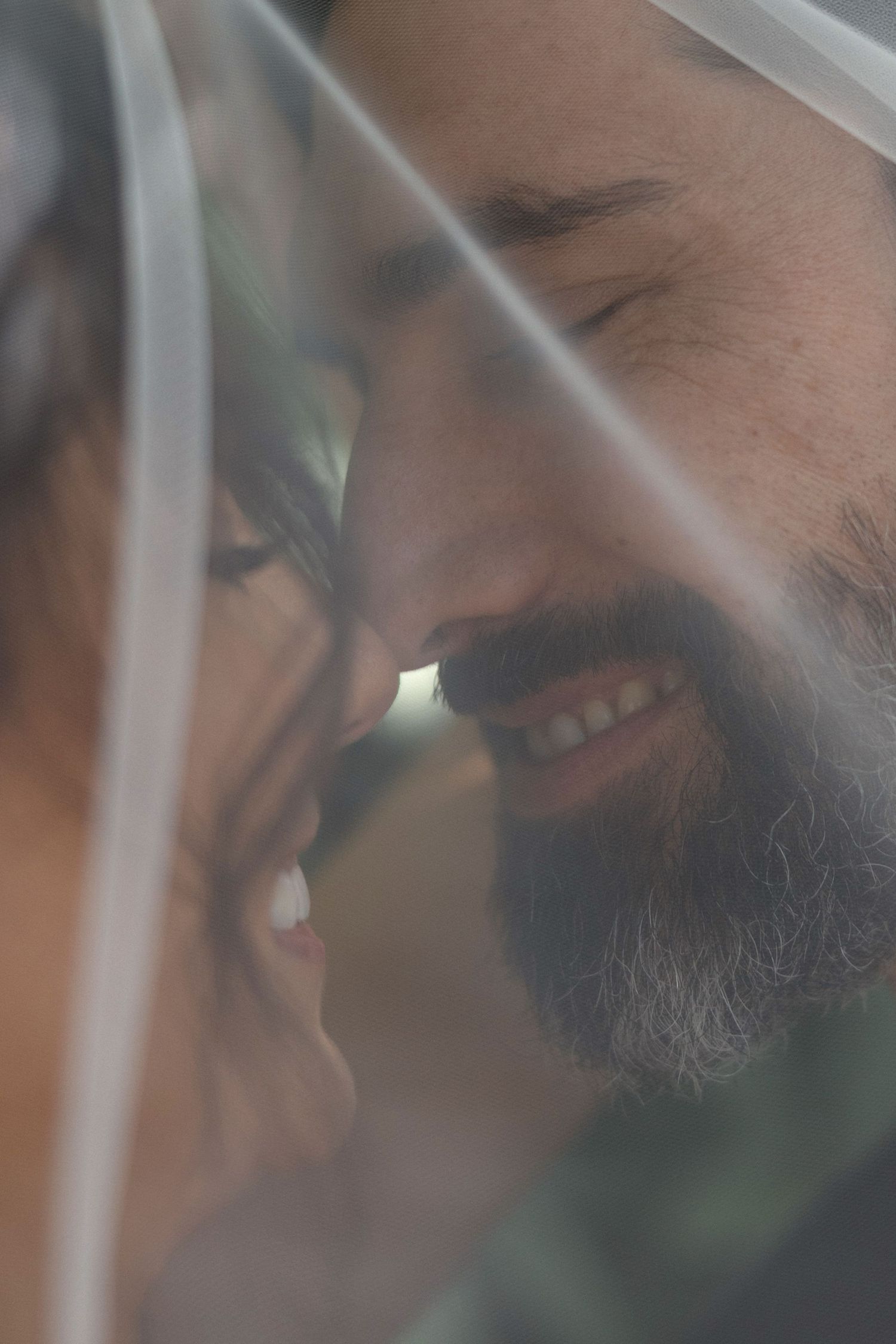 Close-up artistic shot showing intimate smiles and tender moments between a couple.