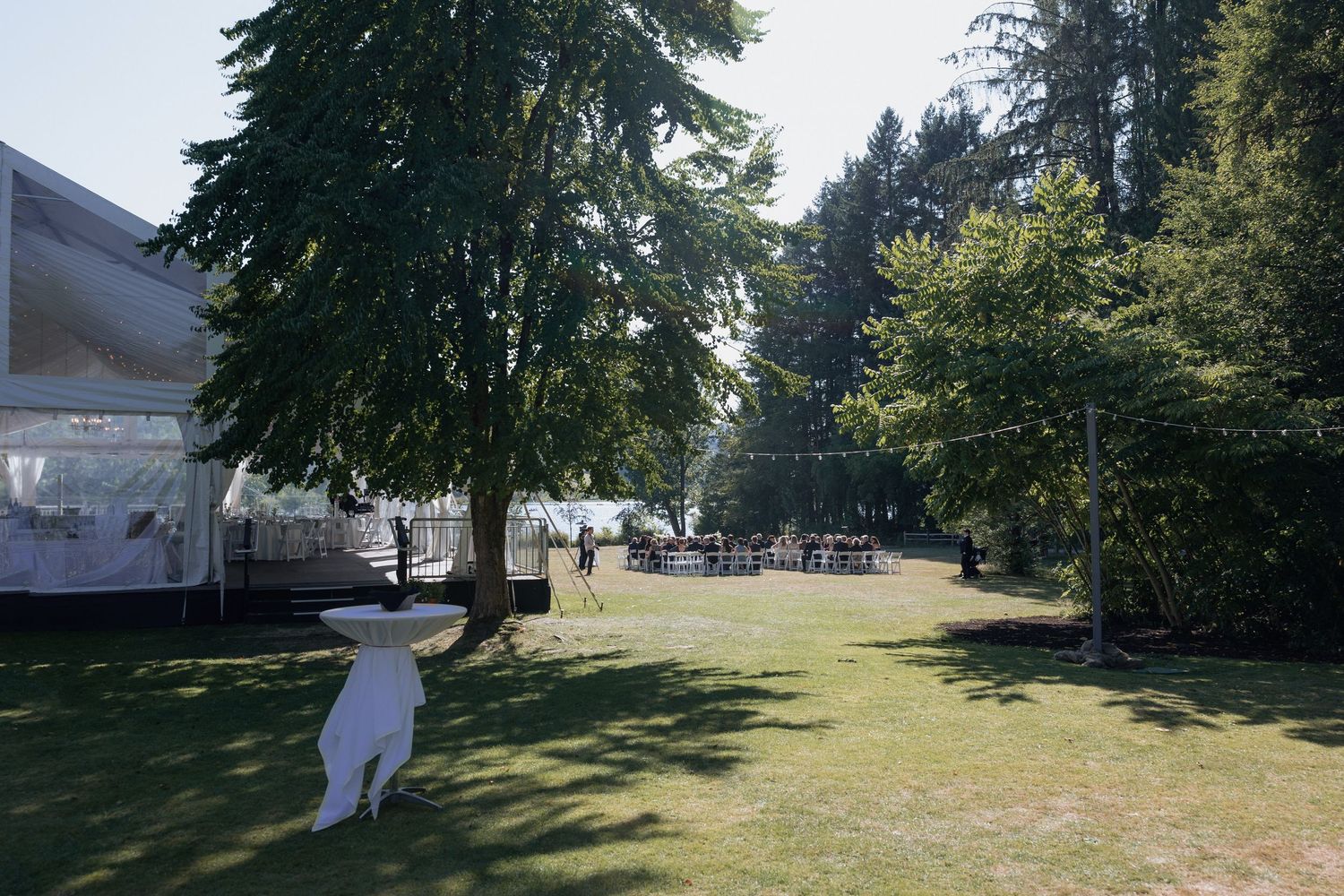 Spacious lawn with white decorations and trees at wedding venue.