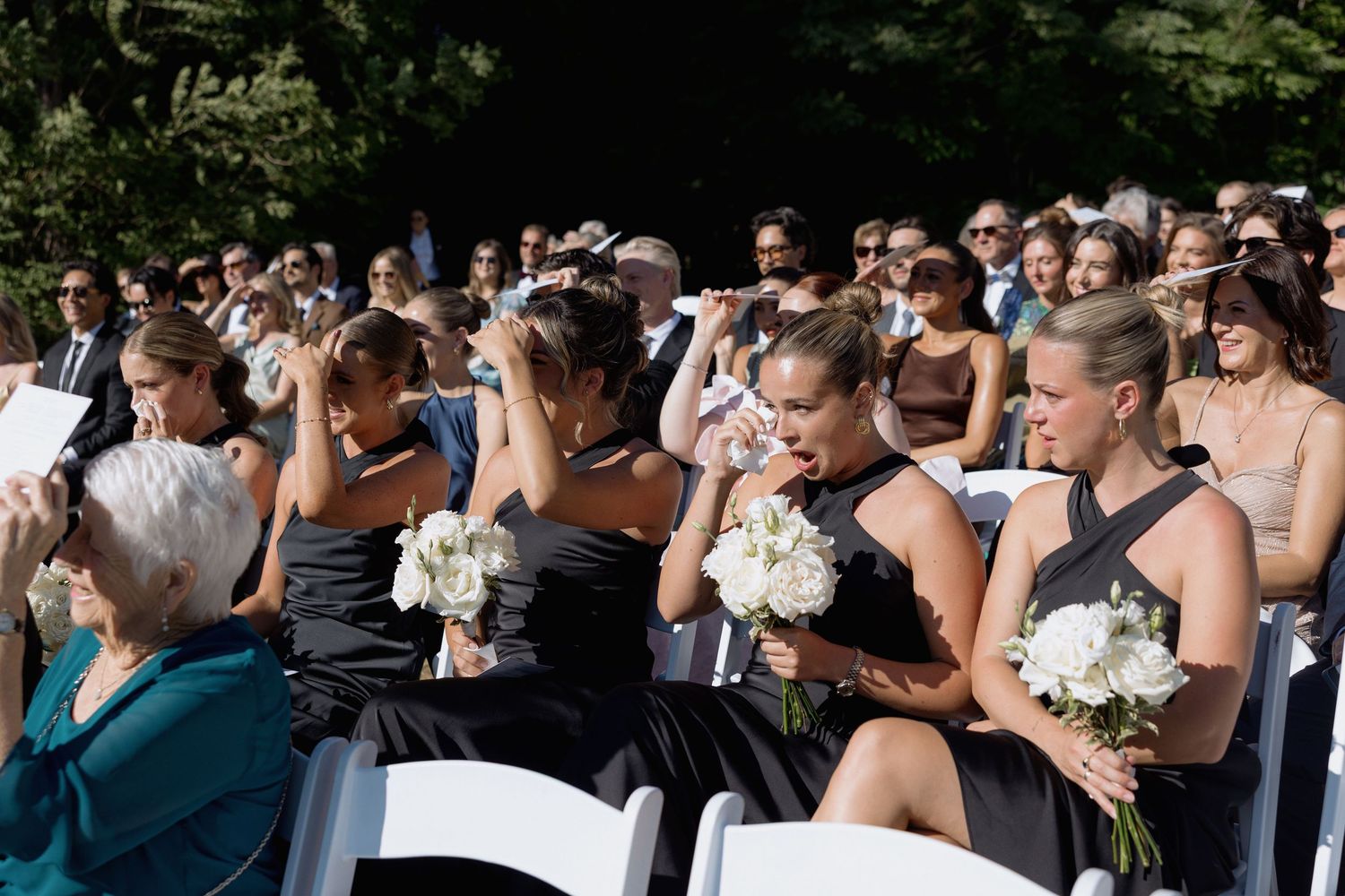 Wedding guests seated in rows watching an outdoor ceremony.