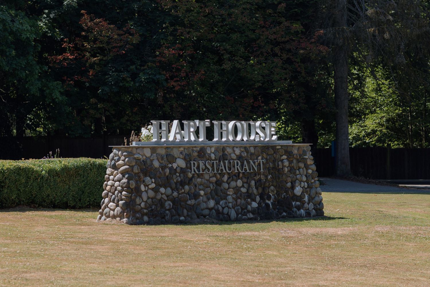 Stone entrance sign for Chart House Restaurant against natural landscape.