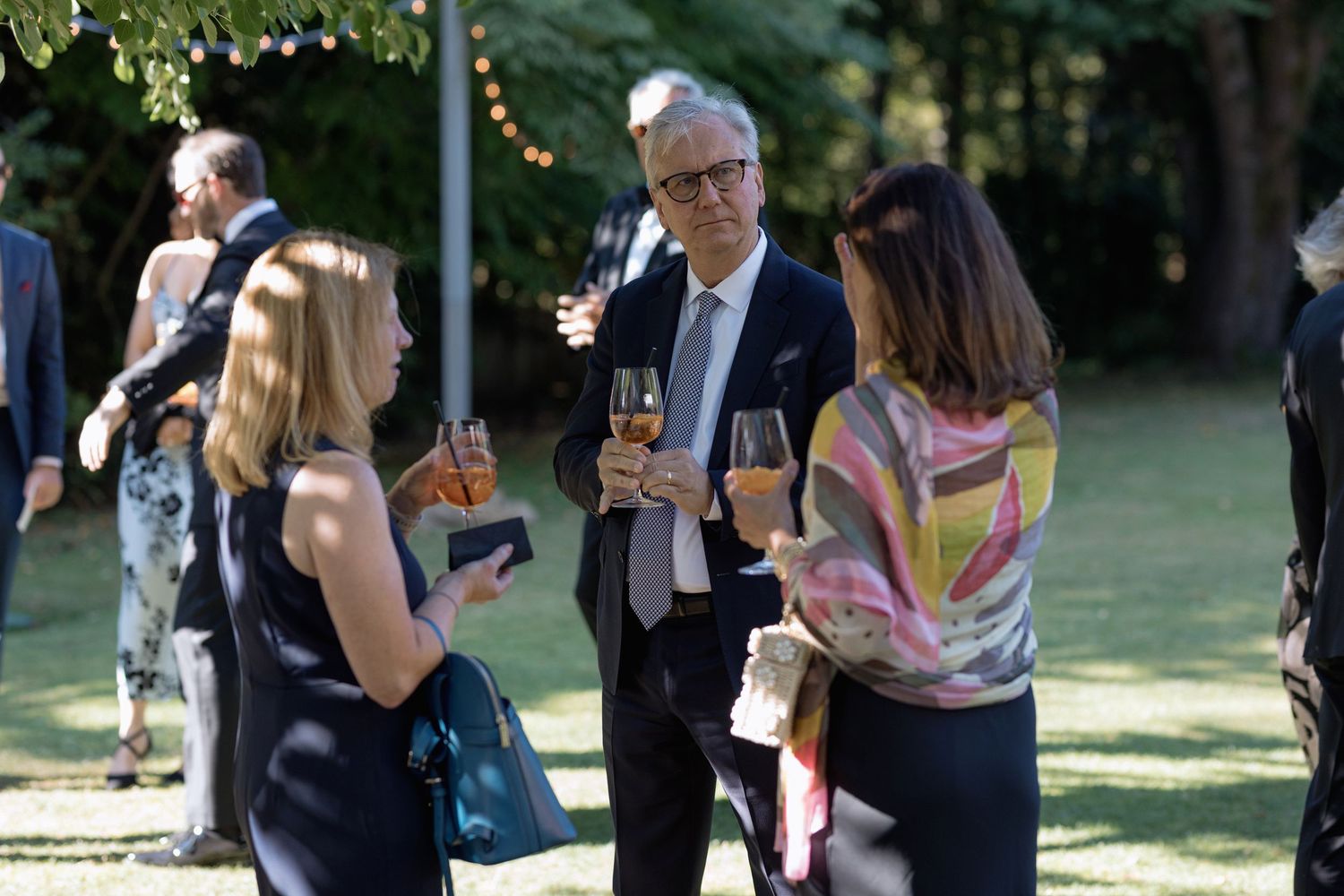 Small group of guests chatting and enjoying drinks at an outdoor reception.
