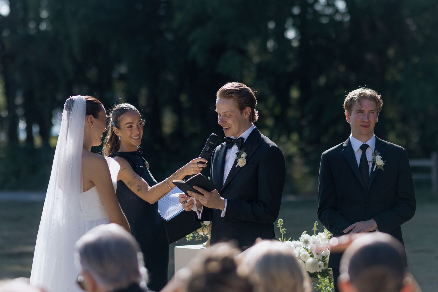 Wedding party members in formal attire during an outdoor ceremony.